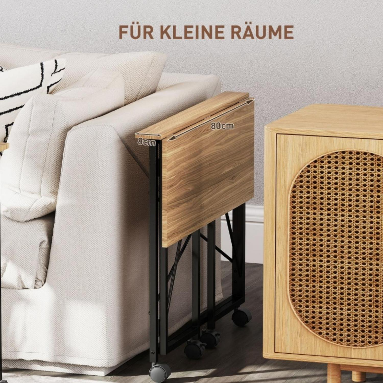 Ein Klapptisch neben einem Sofa und einem Holzschrank. Der Tisch ist braun, hat schwarze Rollbeine. Der Schrank hat eine Korbtür.