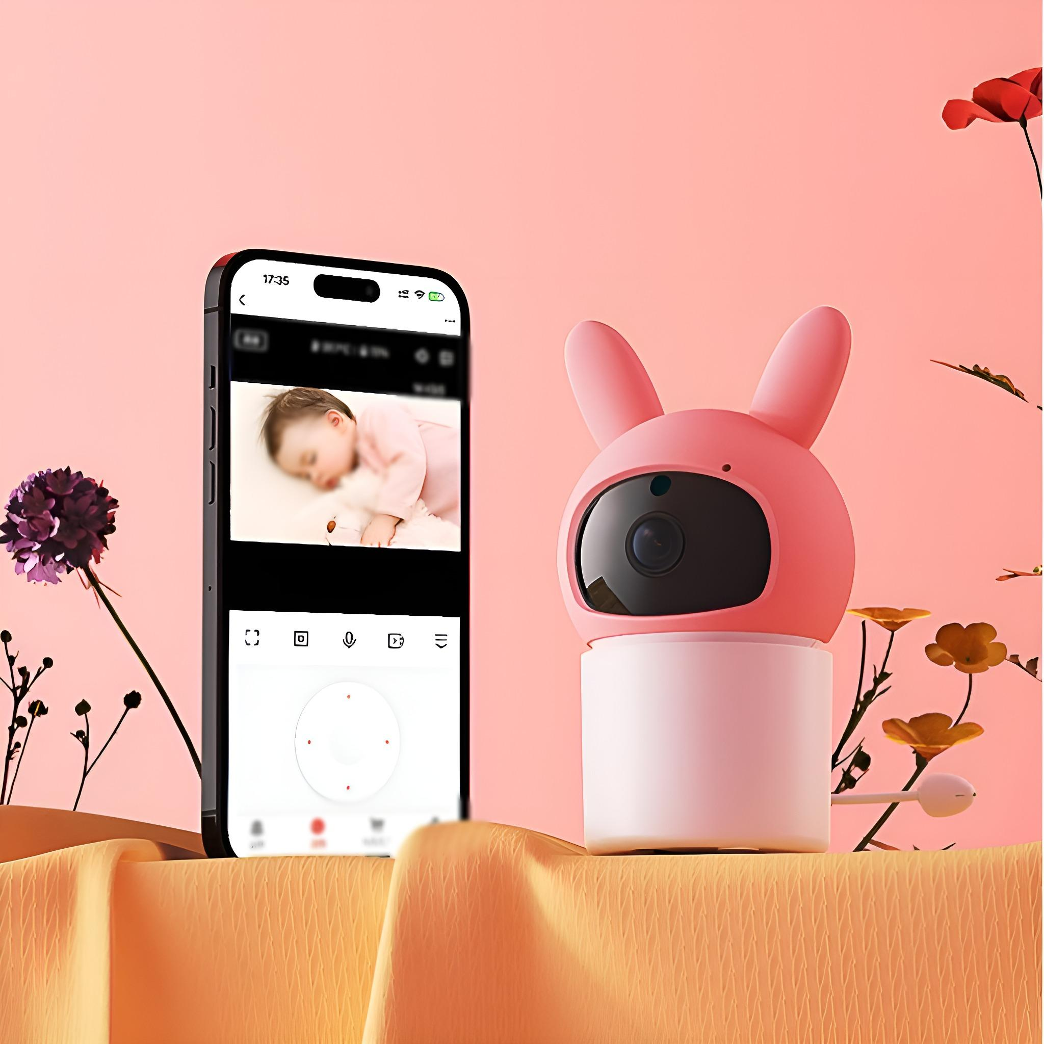 Ein Babyphone in Hasenform mit einem Telefon, das ein Baby auf dem Bildschirm zeigt, und Blumen.