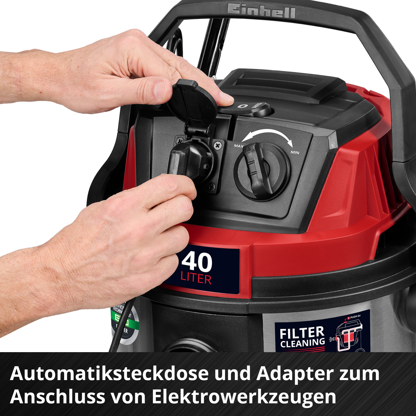 Eine Person, die ein Netzkabel in einen rot-schwarzen Staubsauger steckt. Der Staubsauger hat einen Griff und ein Steuerrad.