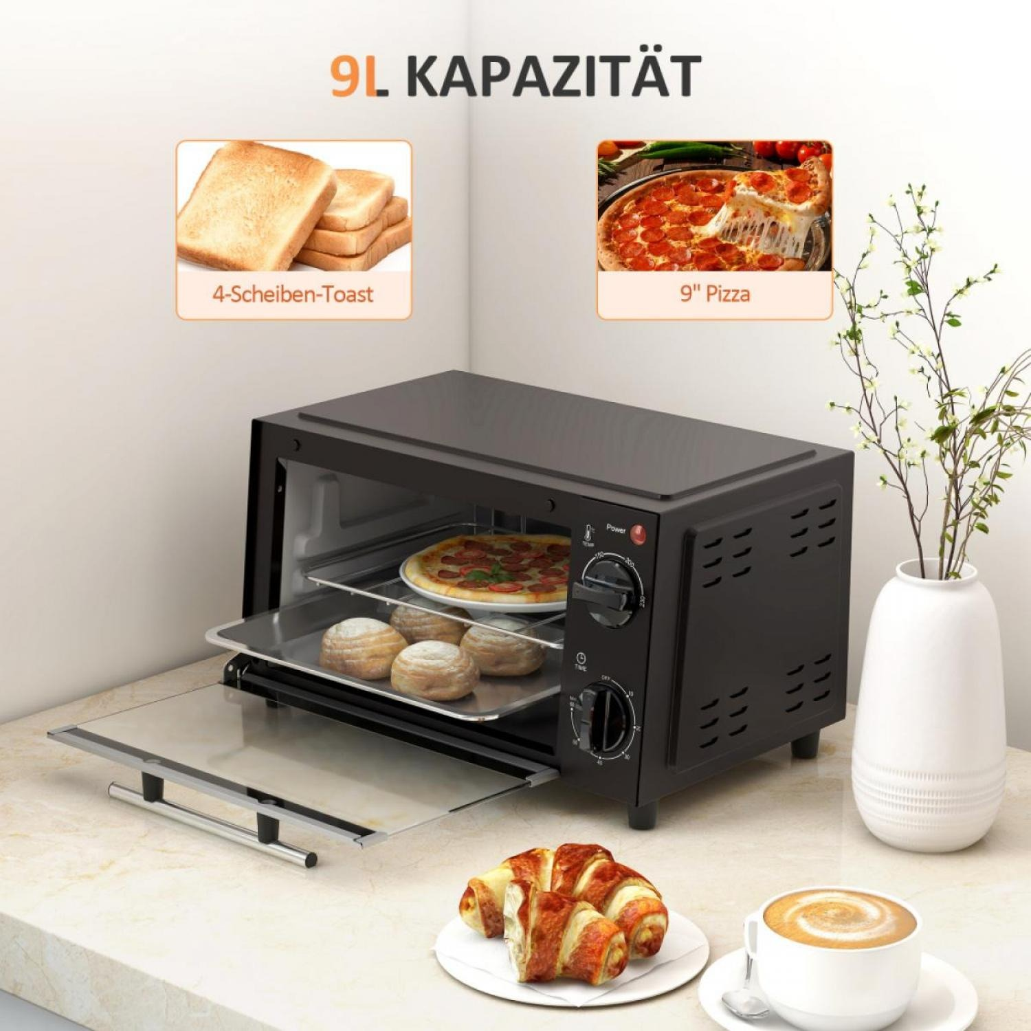 Schwarzer Toaster mit Pizza, Brötchen und Croissant auf einem Tisch. Eine Tasse Kaffee und eine Vase mit Pflanzen sind in der Nähe.