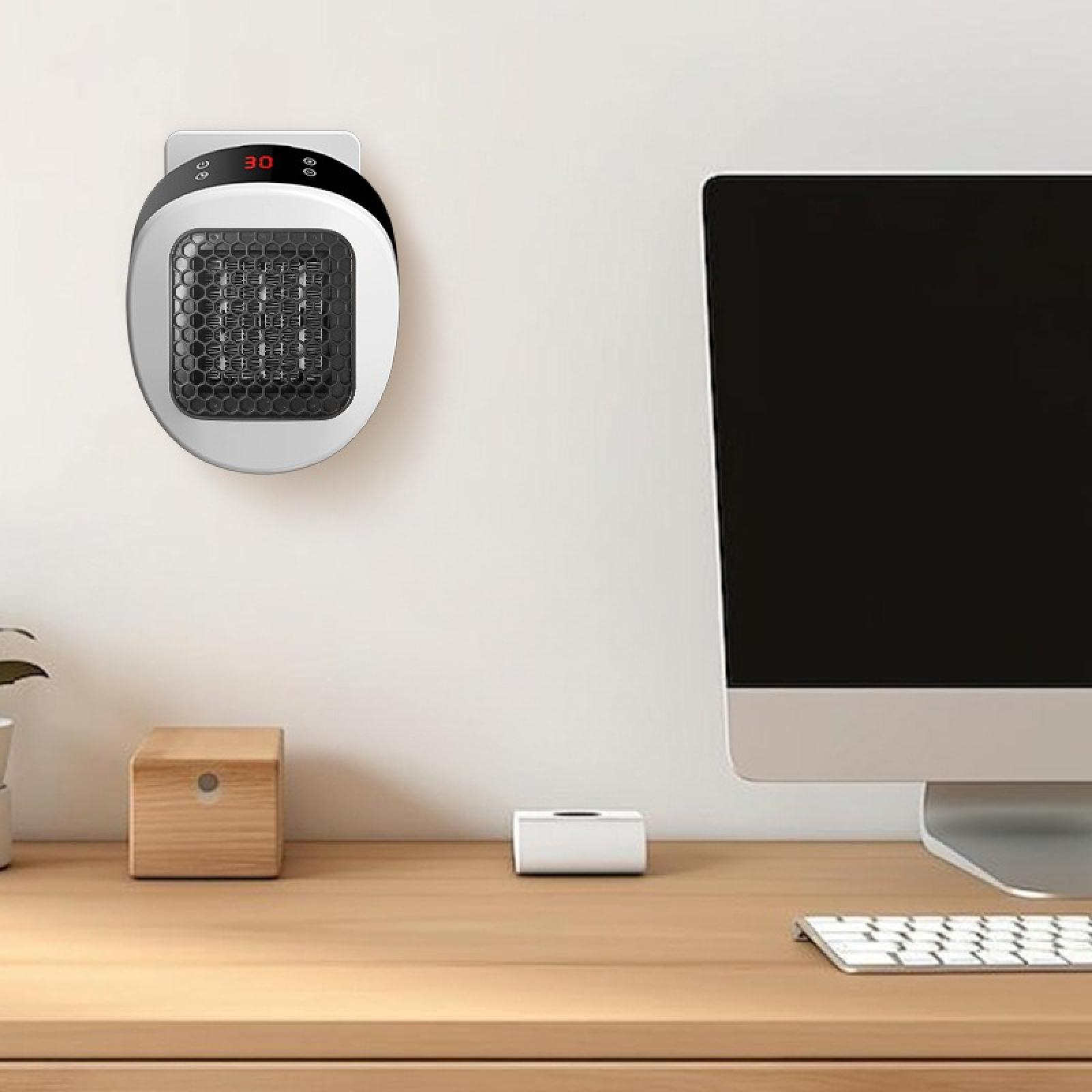 Weißer, an der Wand befestigter Heizlüfter mit der Anzeige '30'. Auf einem Holztisch befinden sich ein Computermonitor und eine Tastatur.