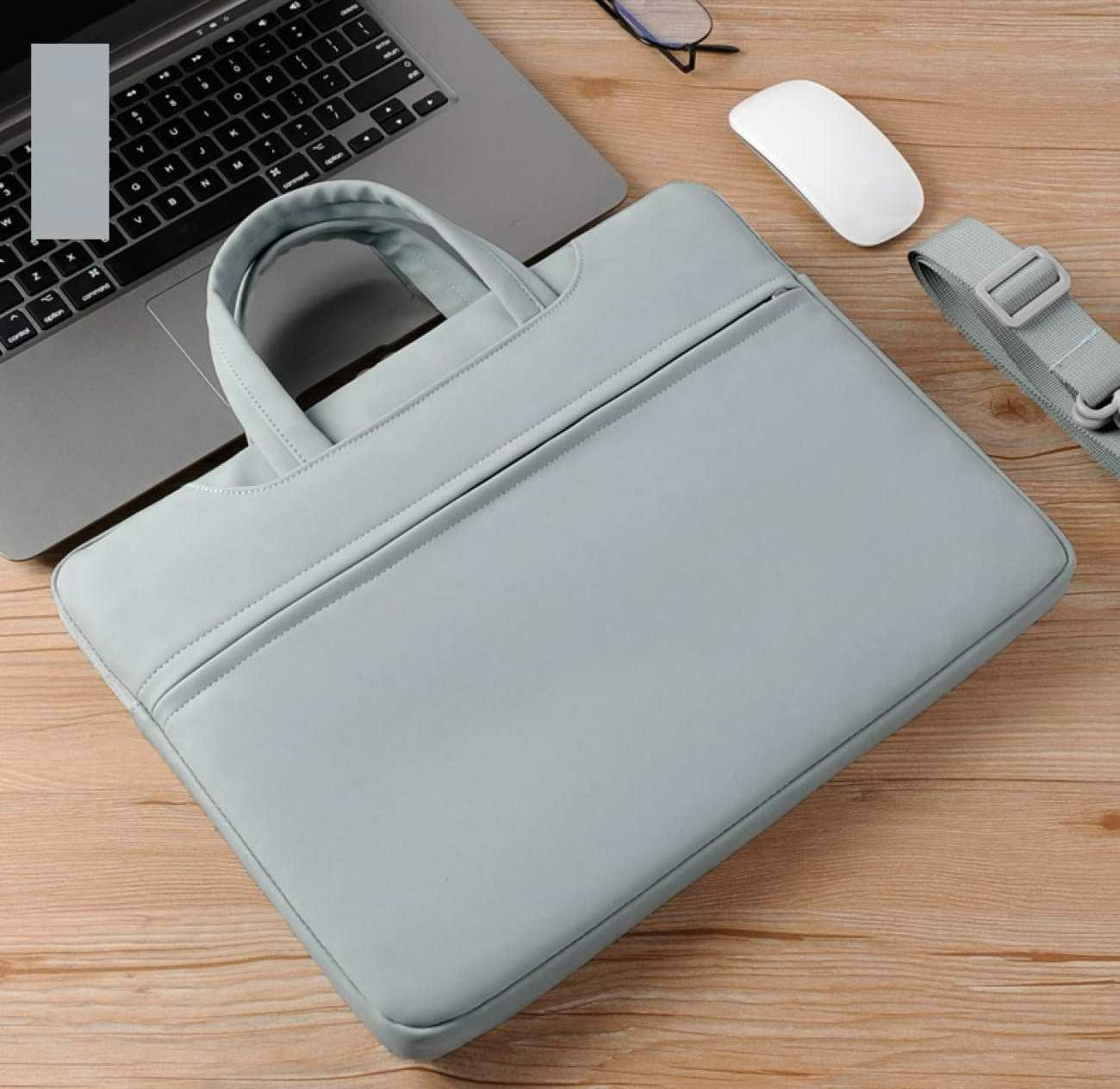Ein Laptop mit grauer Hülle, Maus und Gurt auf einer Holzoberfläche. Auch eine Brille ist im Bild zu sehen.