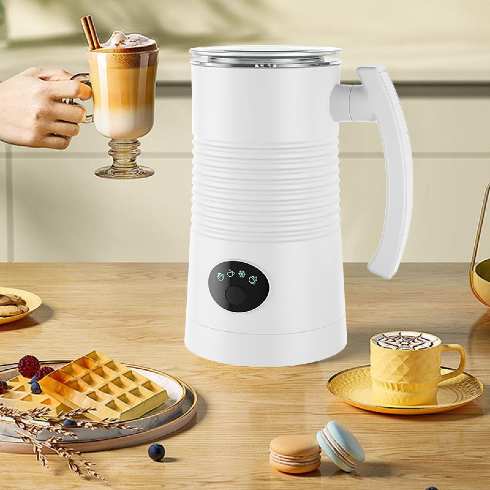 Ein weißer Milchaufschäumer mit Griff auf einem Holztisch, Latte und Waffeln sind sichtbar.