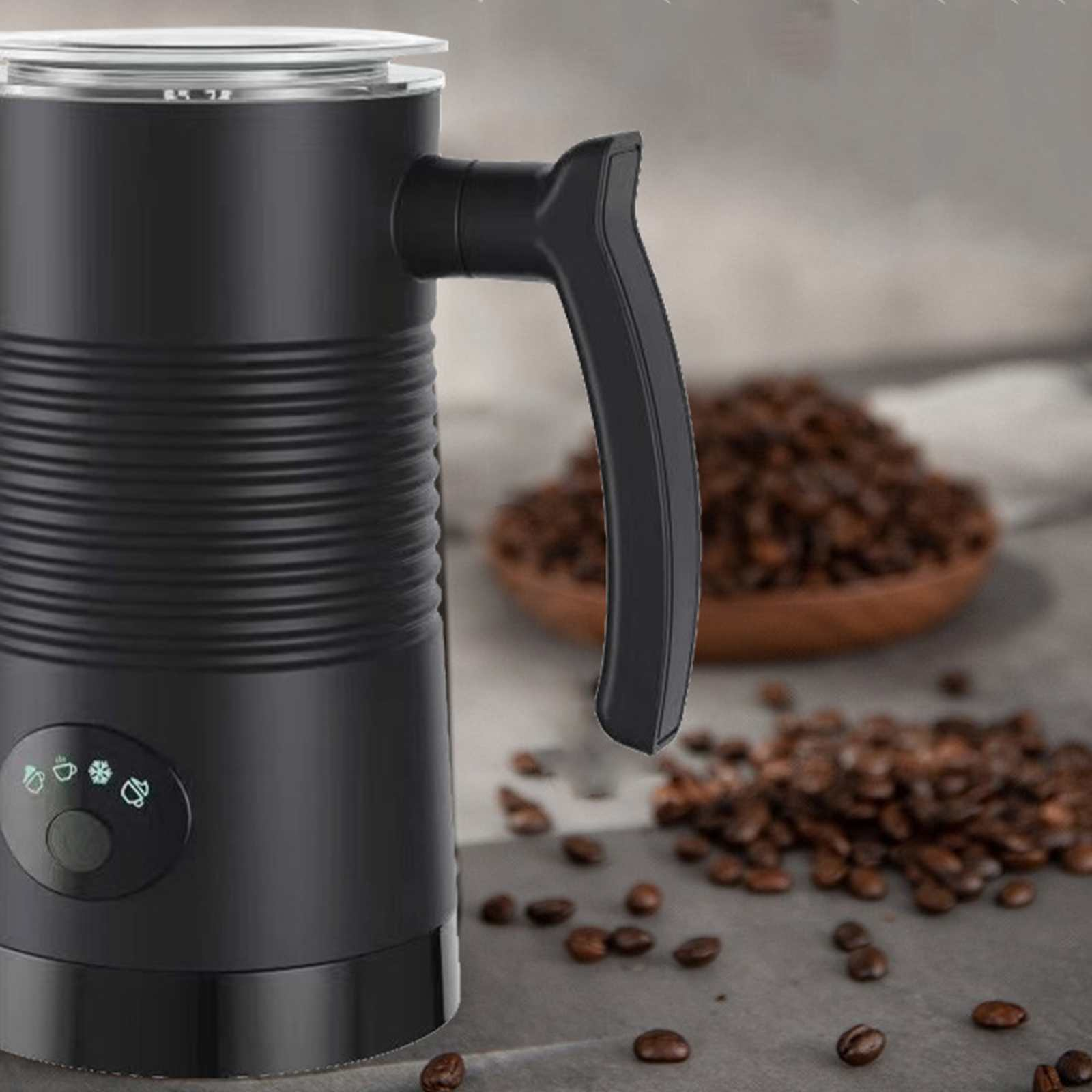 Ein schwarzer Milchaufschäumer mit Griff neben einer Holzschale mit Kaffeebohnen, verstreute Bohnen auf der Oberfläche.