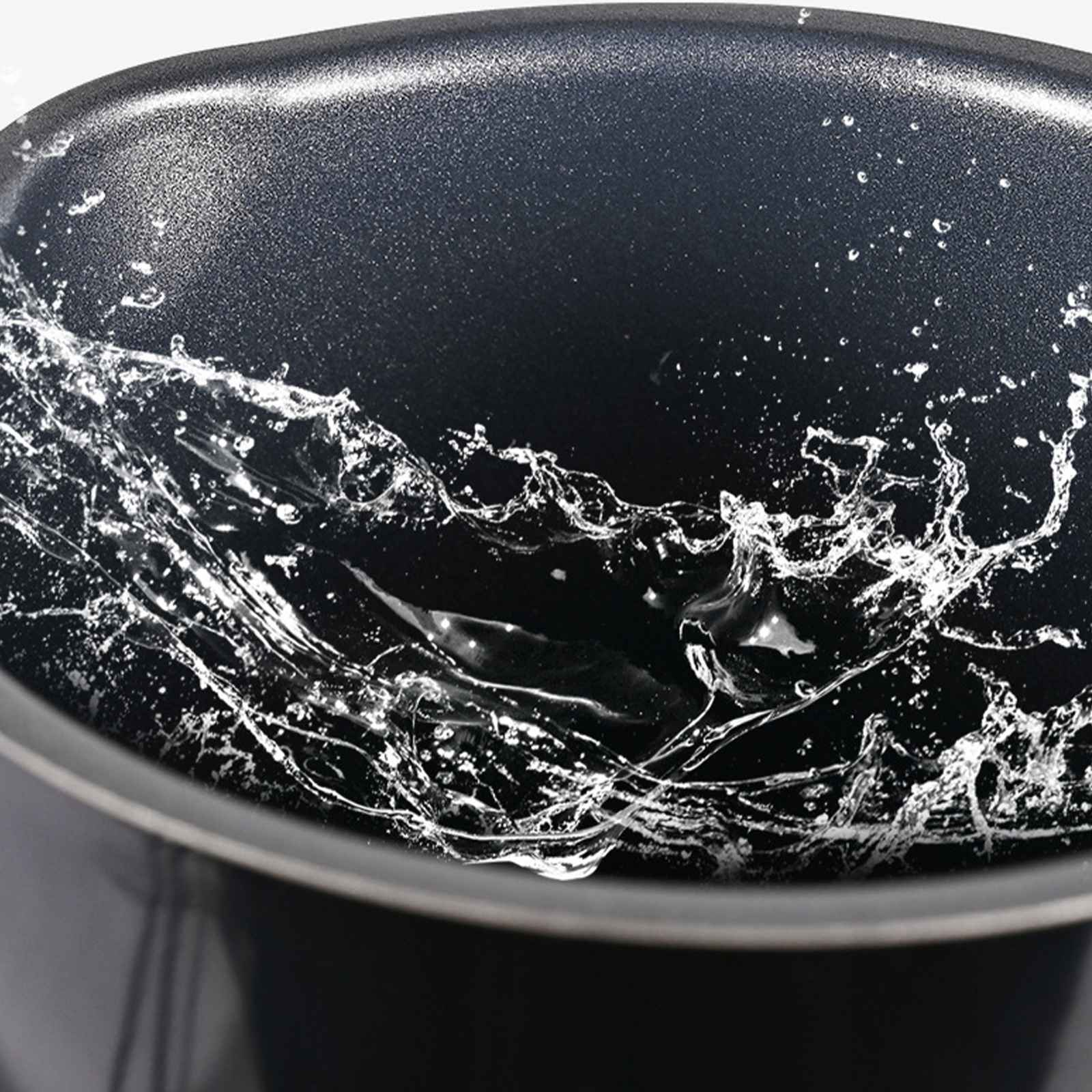 Nahaufnahme einer dunklen Schüssel mit spritzendem Wasser. Klare Wassertropfen und -ströme erzeugen dynamische Muster.