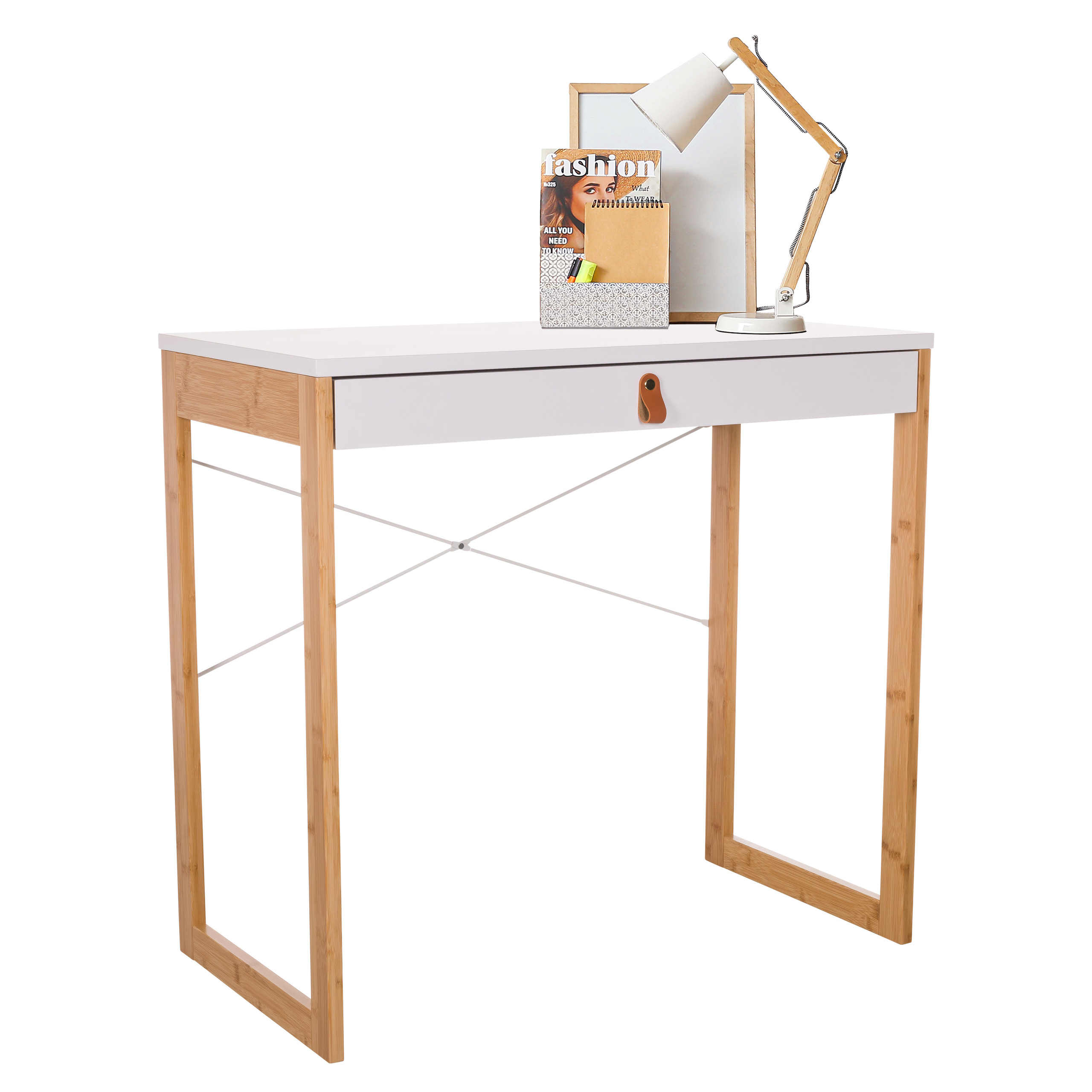 Weißer Schreibtisch mit Bambusbeinen. Eine Lampe und eine Zeitschrift liegen darauf. Schublade mit braunem Ledergriff.