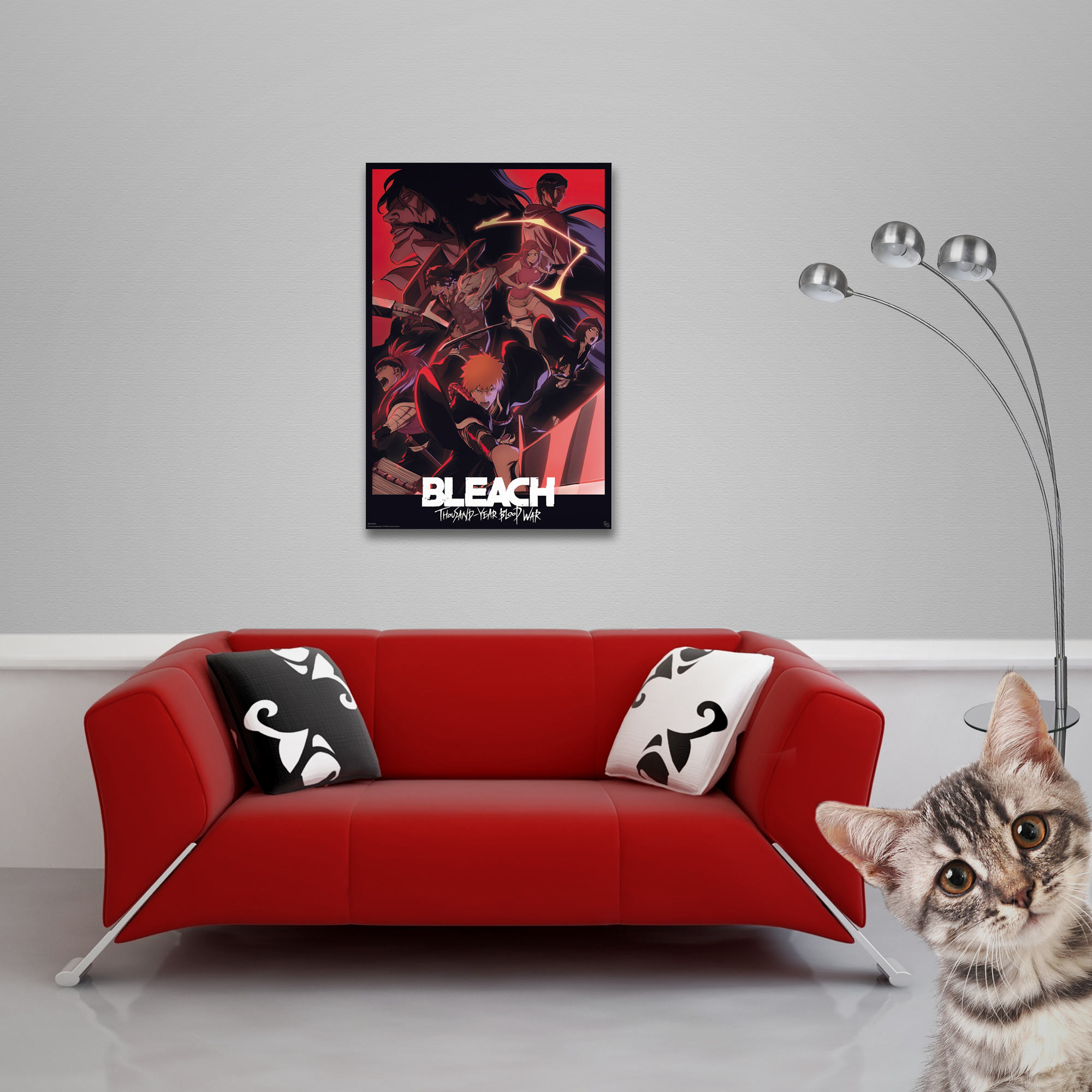 Ein rotes Sofa mit Kissen steht unter einem Bleach-Poster. Eine Katze lugt von rechts. Eine Lampe ist im Hintergrund.