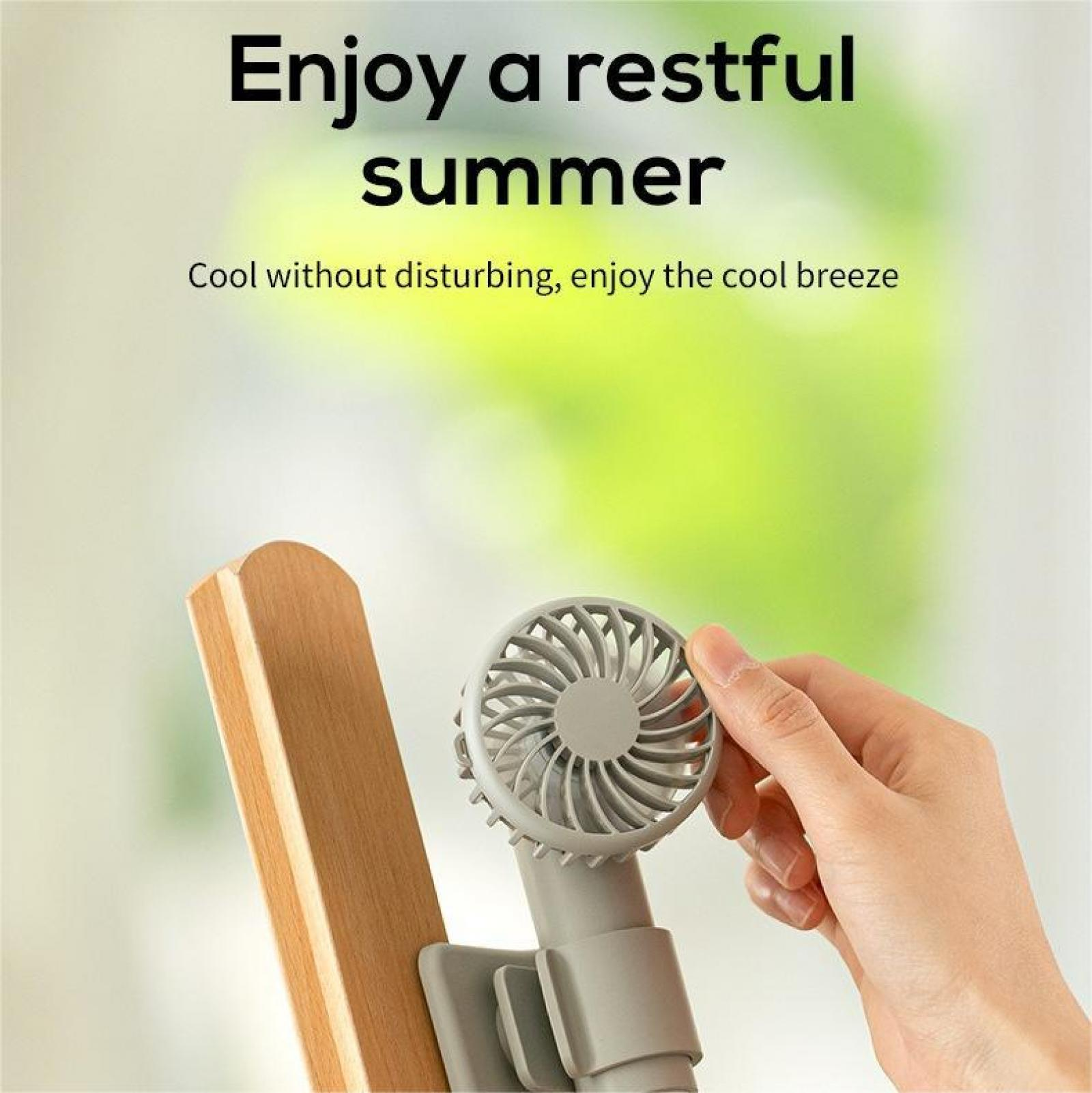 Hand hält einen grauen Ventilator, der an Holz befestigt ist. Text sagt 'Genieße einen erholsamen Sommer'. Hintergrund ist grün.