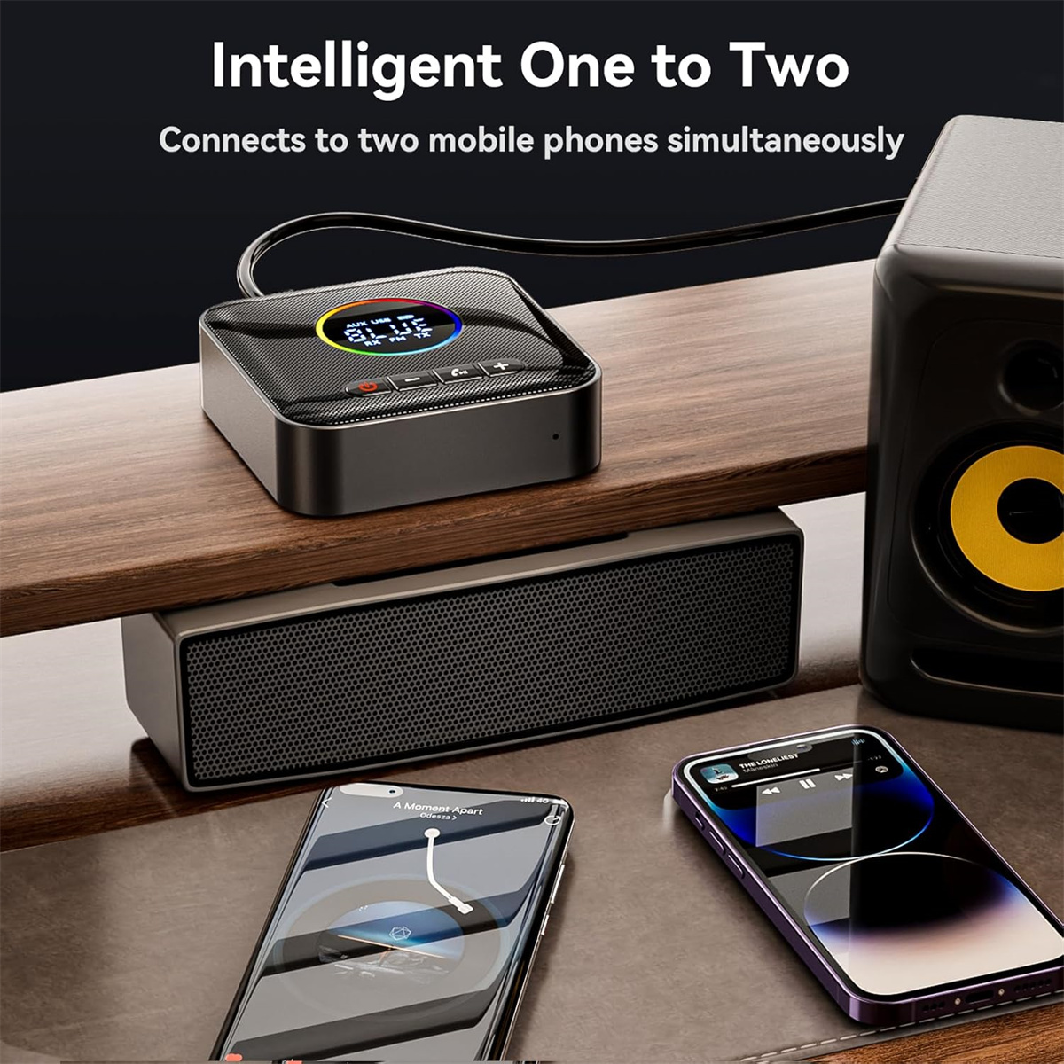 Ein Gerät mit Bildschirm, zwei Smartphones, ein Lautsprecher und eine Soundbar liegen auf einer Holzoberfläche. Das Gerät verbindet zwei Telefone.