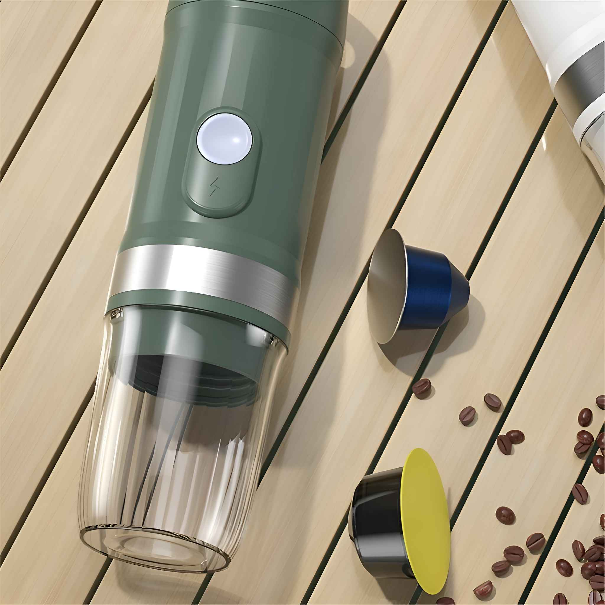 Grüner und silberner Kaffeezubereiter mit Kapseln und Kaffeebohnen auf einer Holzoberfläche. Eine Kapsel ist gelb, die andere blau.