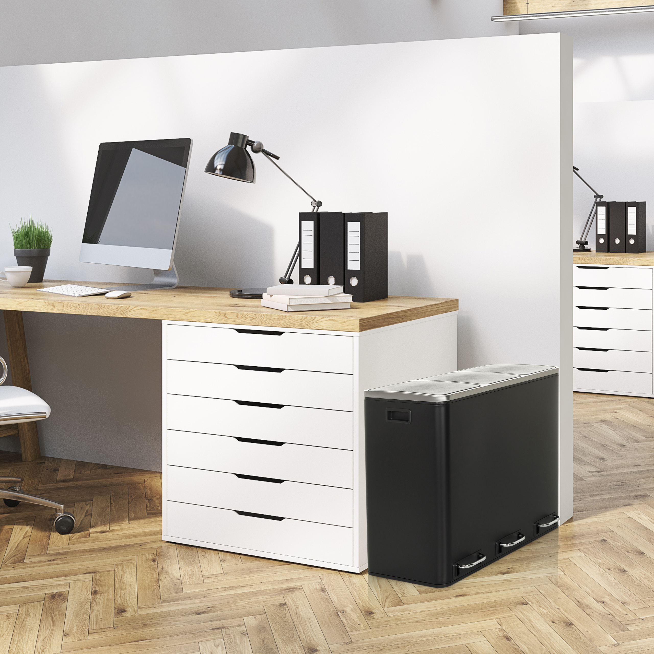 Büroszene mit Schreibtisch, Computer, Lampe und schwarzem Mülleimer. Weiße Schubladen und Holzboden. Ein zweiter Schreibtisch ist auch im Bild.