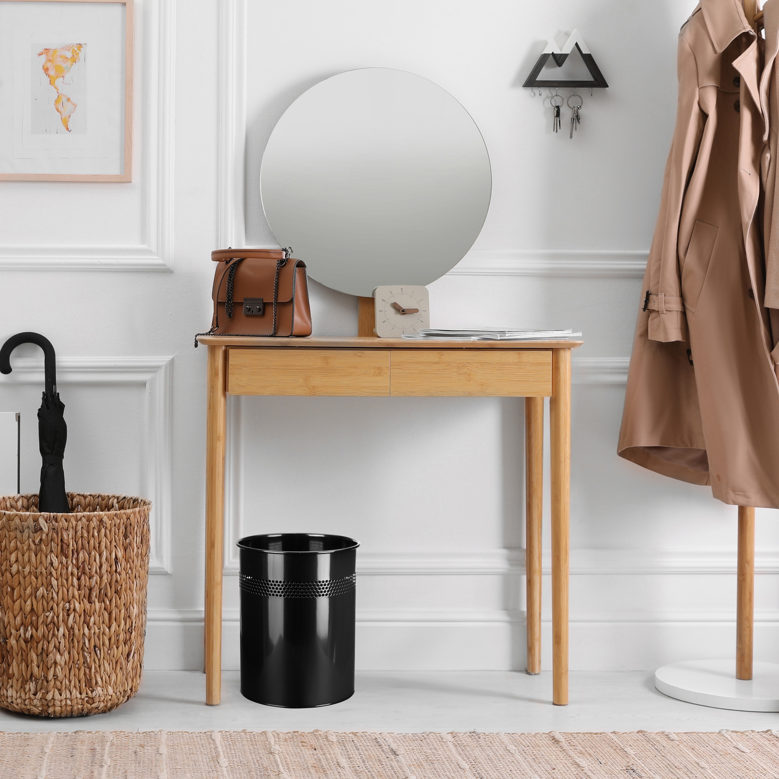 Ein Foyer mit Holztisch, Spiegel, Tasche, Mantel, Mülleimer und Regenschirm in einem Weidenkorb.