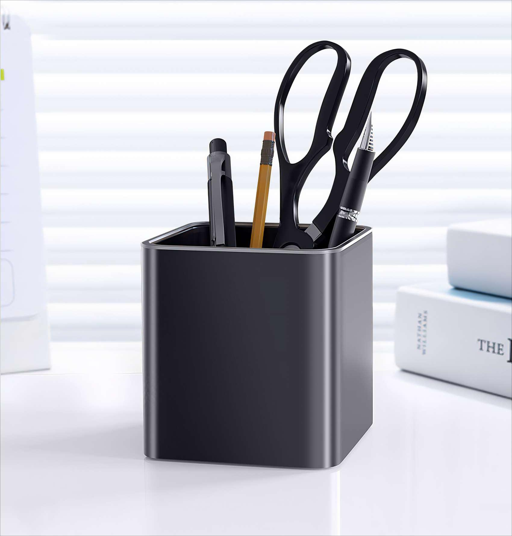 Schwarzer Schreibtisch-Organizer mit Stiften, Bleistift und Schere. Im Hintergrund ein helles Fenster und Bücher. Weißer Schreibtisch.