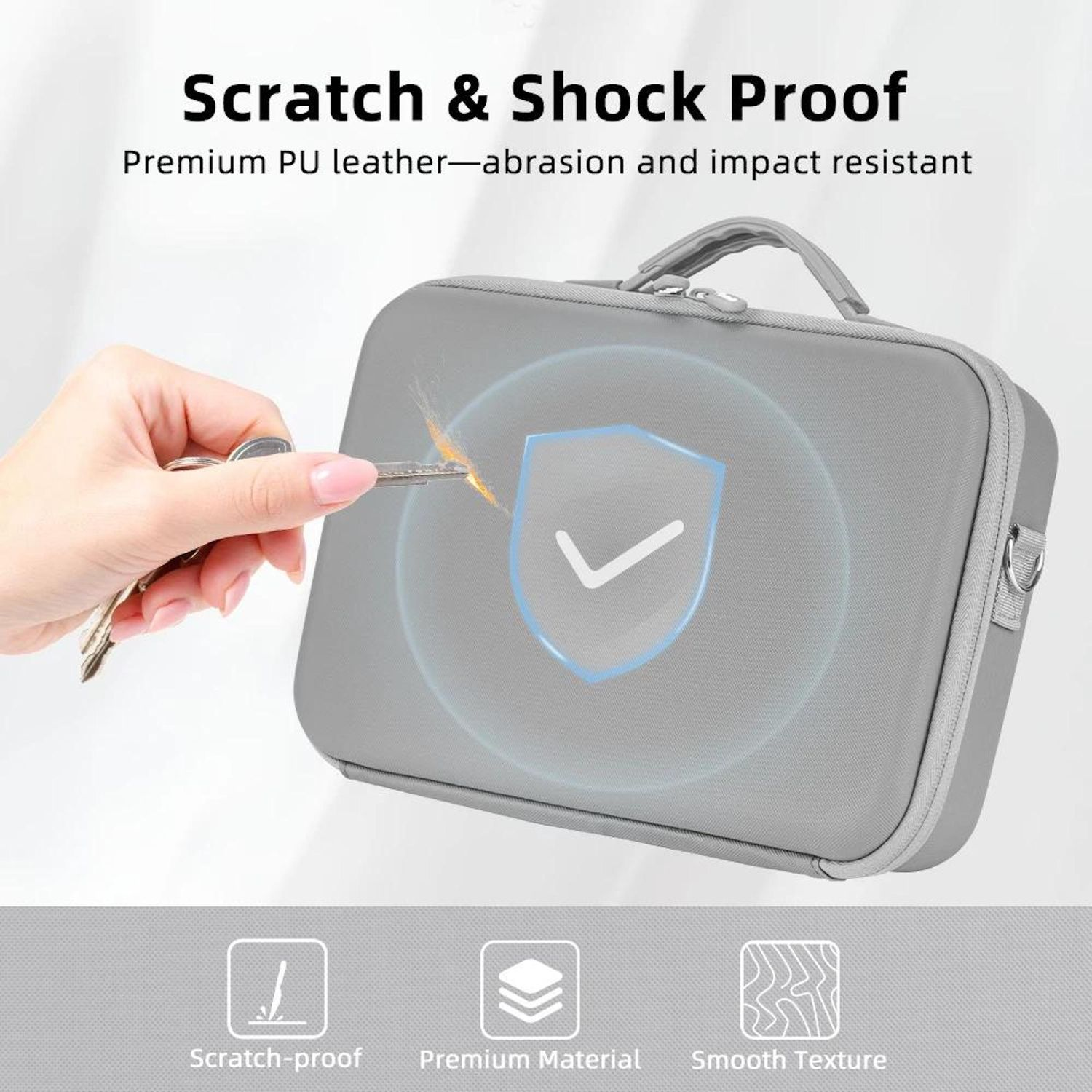 Ein grauer Koffer wird mit einem Schlüssel getestet. Der Koffer hat ein Schildsymbol, und der Text lautet 'Scratch & Shock Proof'.
