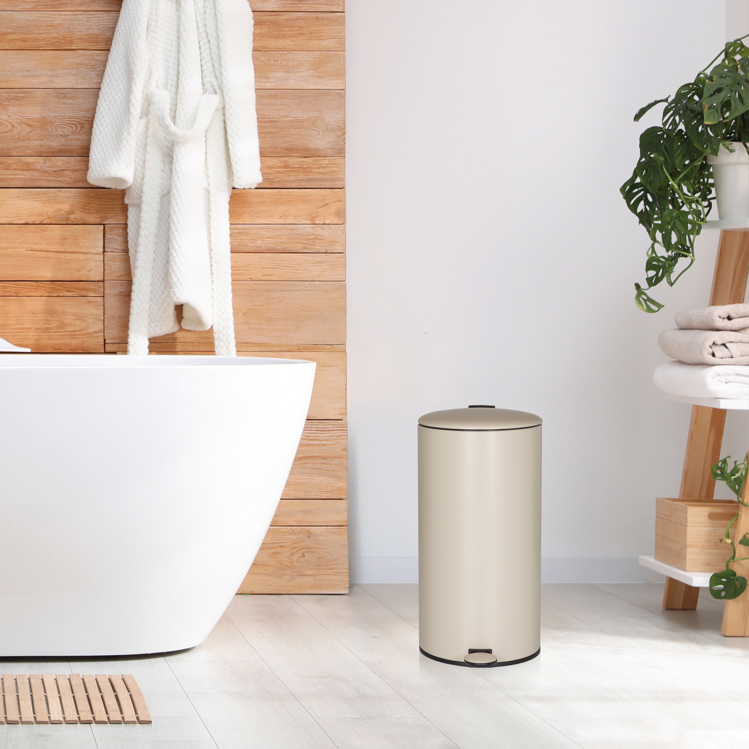 Ein Badezimmer mit weißer Wanne, Bademantel und Mülleimer. Holzakzente und eine Pflanze sind ebenfalls sichtbar.