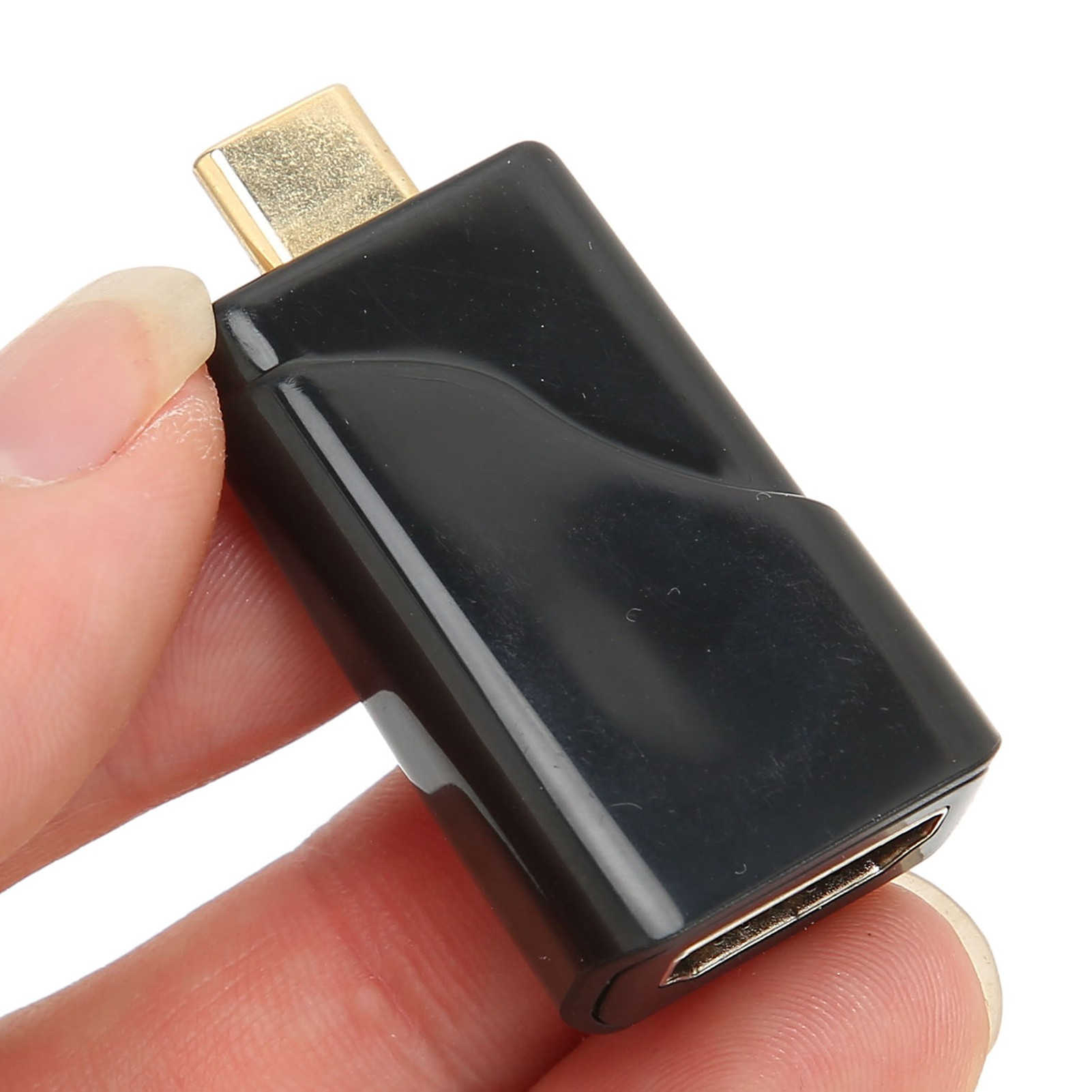 Ein schwarzer USB-C-auf-HDMI-Adapter wird von einer Hand gehalten. Goldener Stecker oben.