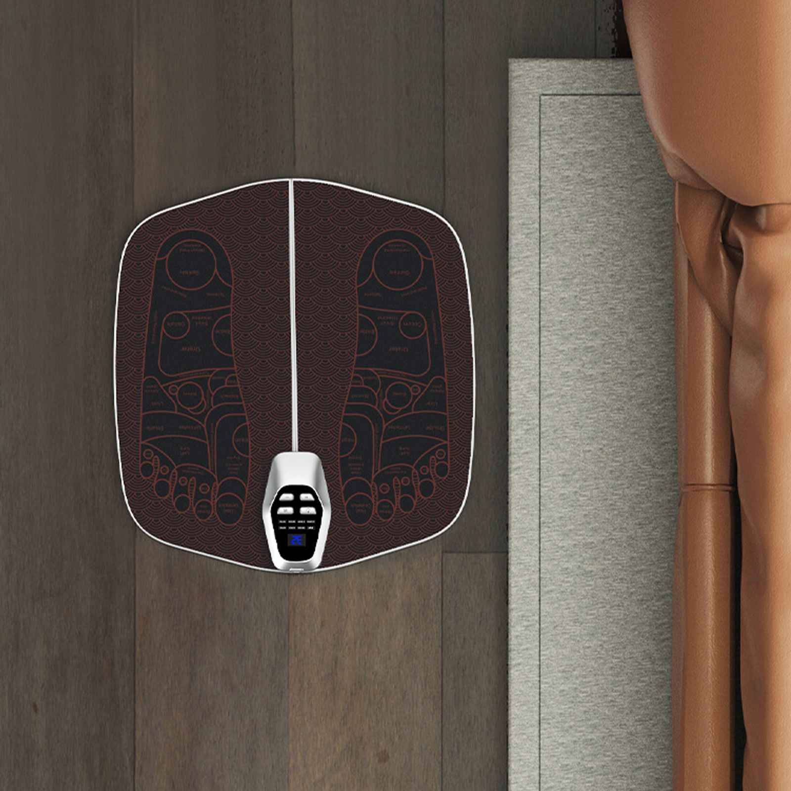 Fußmassage-Matte mit Steuereinheit, Fußdiagramm. Braune Holzoberfläche, grauer Stoff und Leder im Hintergrund.