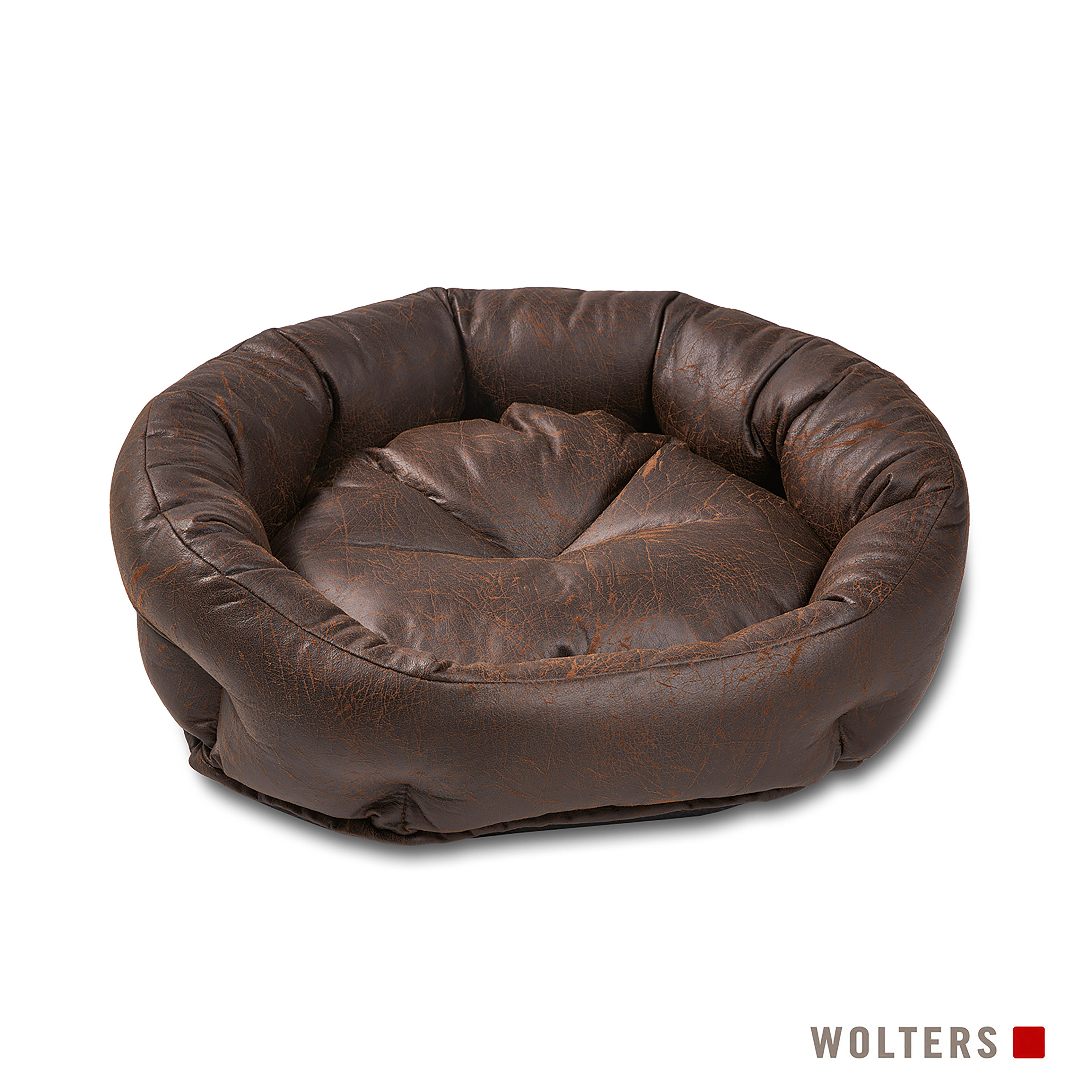 Ein braunes Leder-Hundebett mit runder Form. Das Bett steht auf einer weißen Oberfläche. Das Wolters-Logo ist sichtbar.