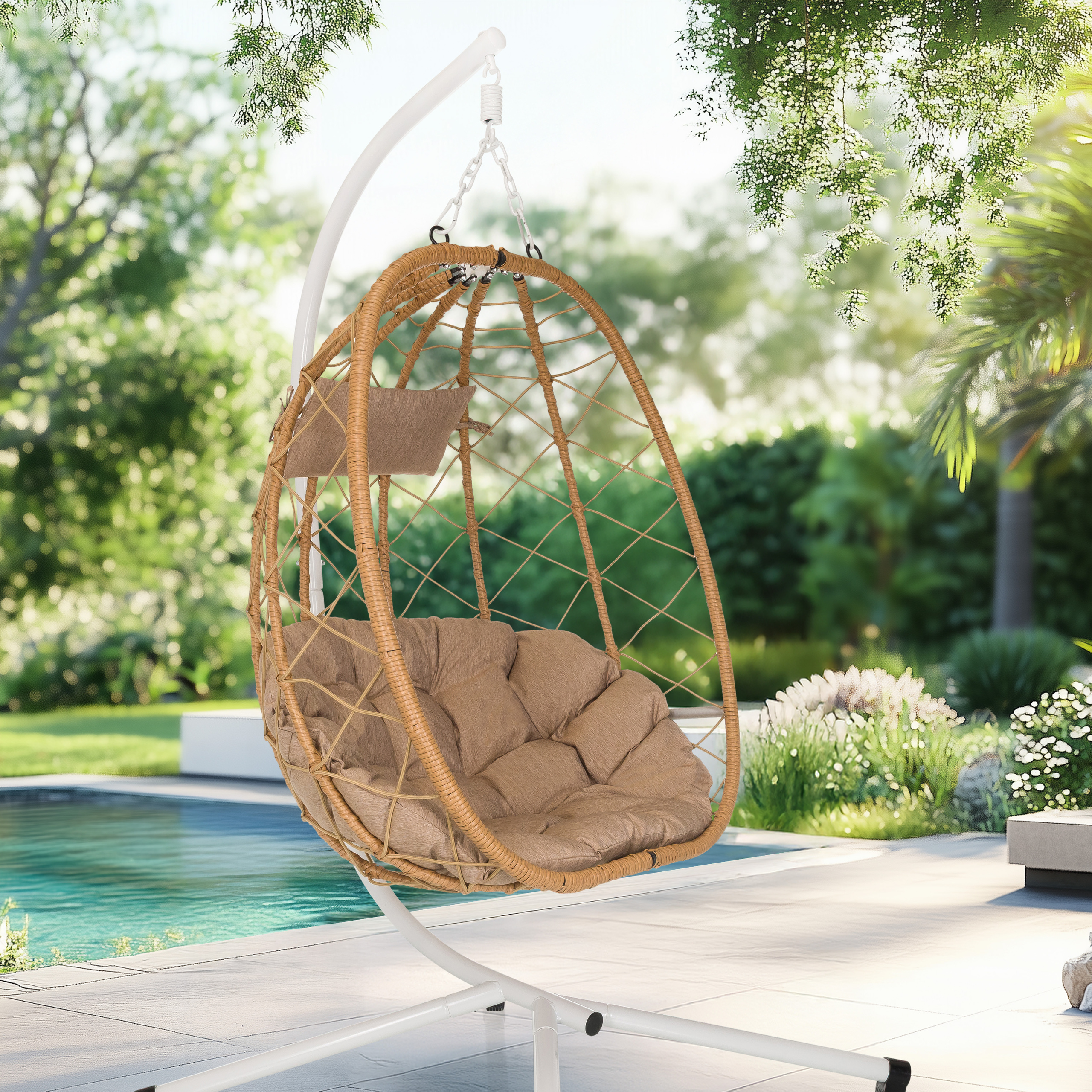 Ein hängender Korbstuhl mit Kissen befindet sich in einem Garten. Im Hintergrund befindet sich ein Pool. Grüne Bäume und Pflanzen umgeben die Szene.