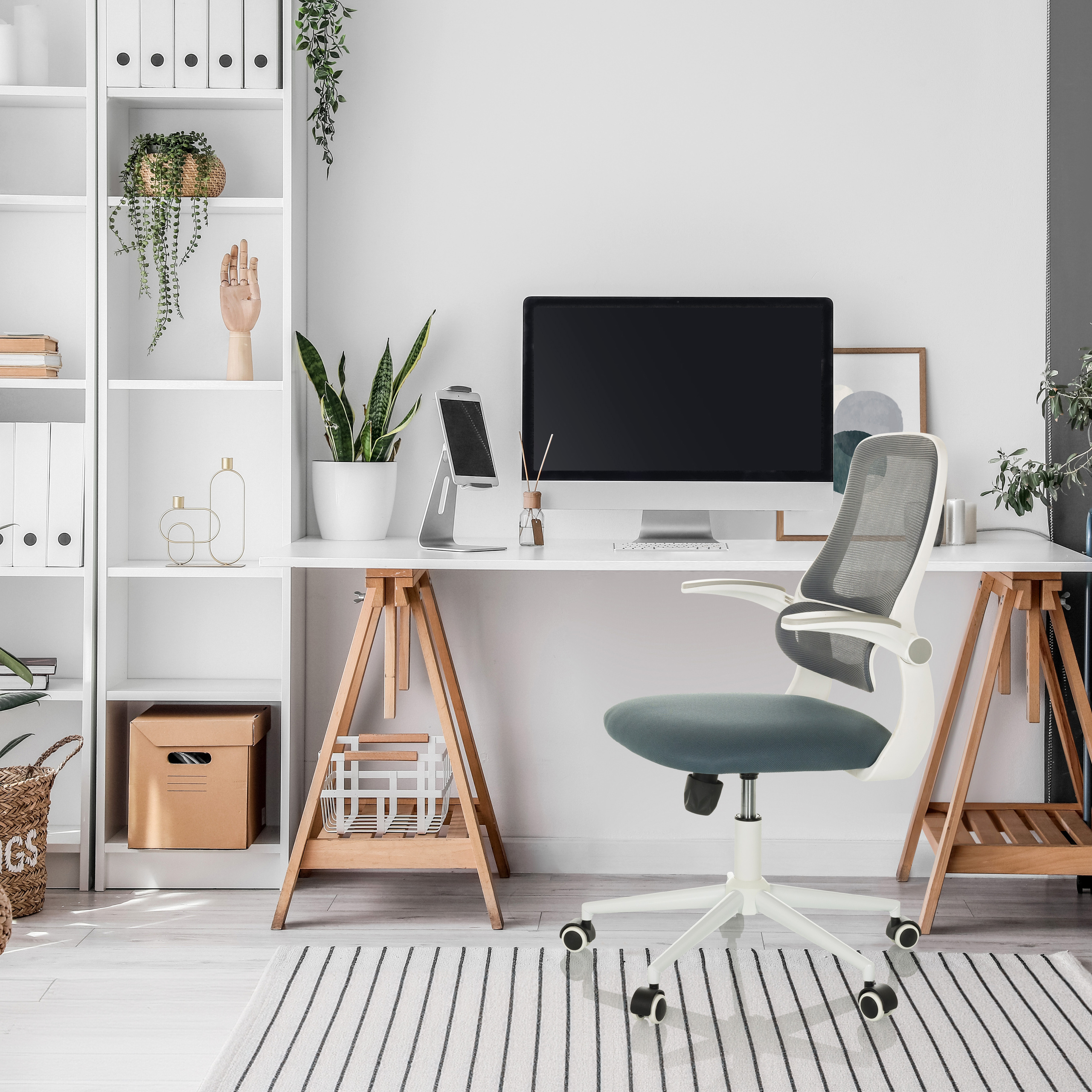Hombüro mit weißem Schreibtisch, Stuhl und Regalen. Auf dem Schreibtisch befinden sich ein Computer, Pflanzen und Dekoration.