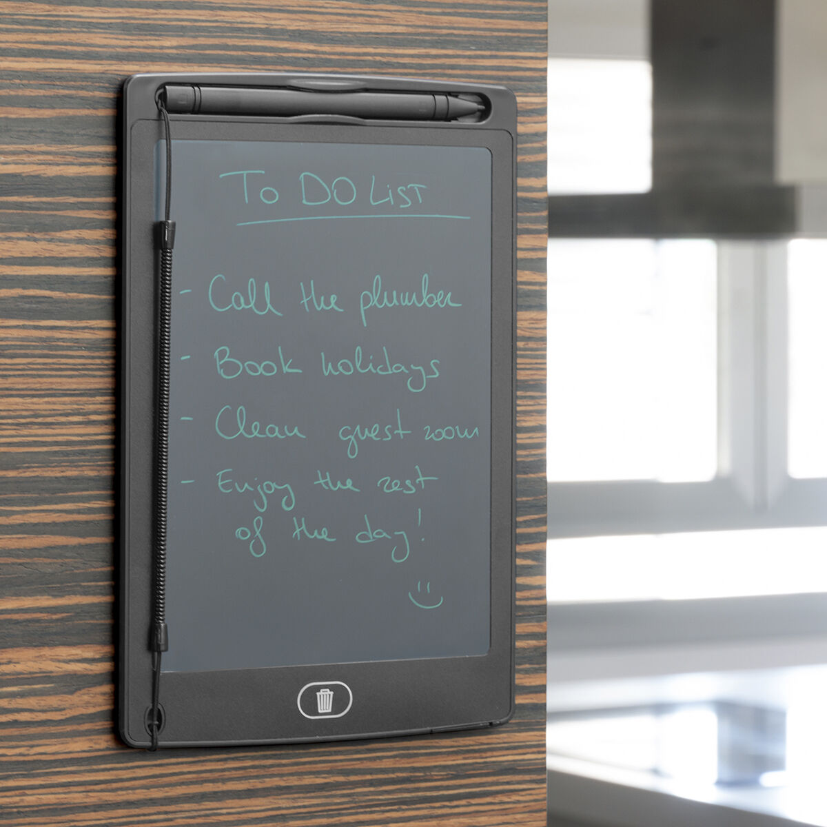 Un blocco note digitale nero con una 'Lista delle cose da fare' scritta in verde acqua. L'elenco include: chiamare l'idraulico, prenotare le vacanze, pulire la camera degli ospiti, godersi la giornata.