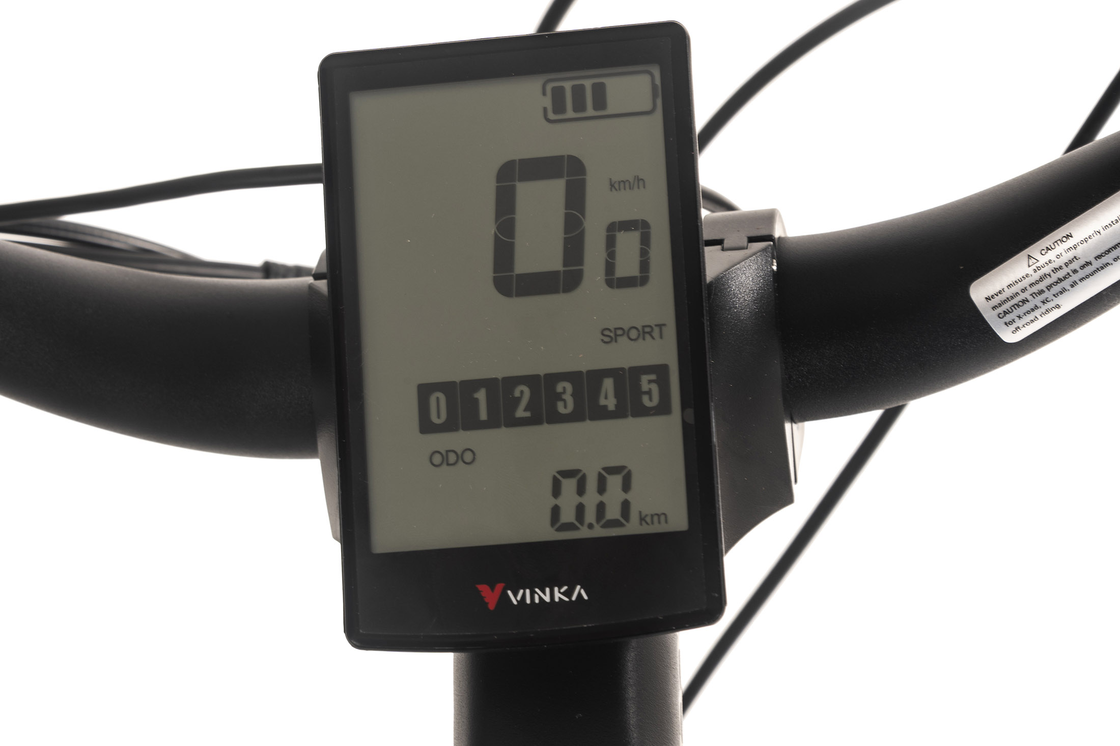 Nahaufnahme eines E-Bike-Displays mit Geschwindigkeit, Akkuladestand und anderen Messwerten. Lenker und Warnschild sind ebenfalls sichtbar.