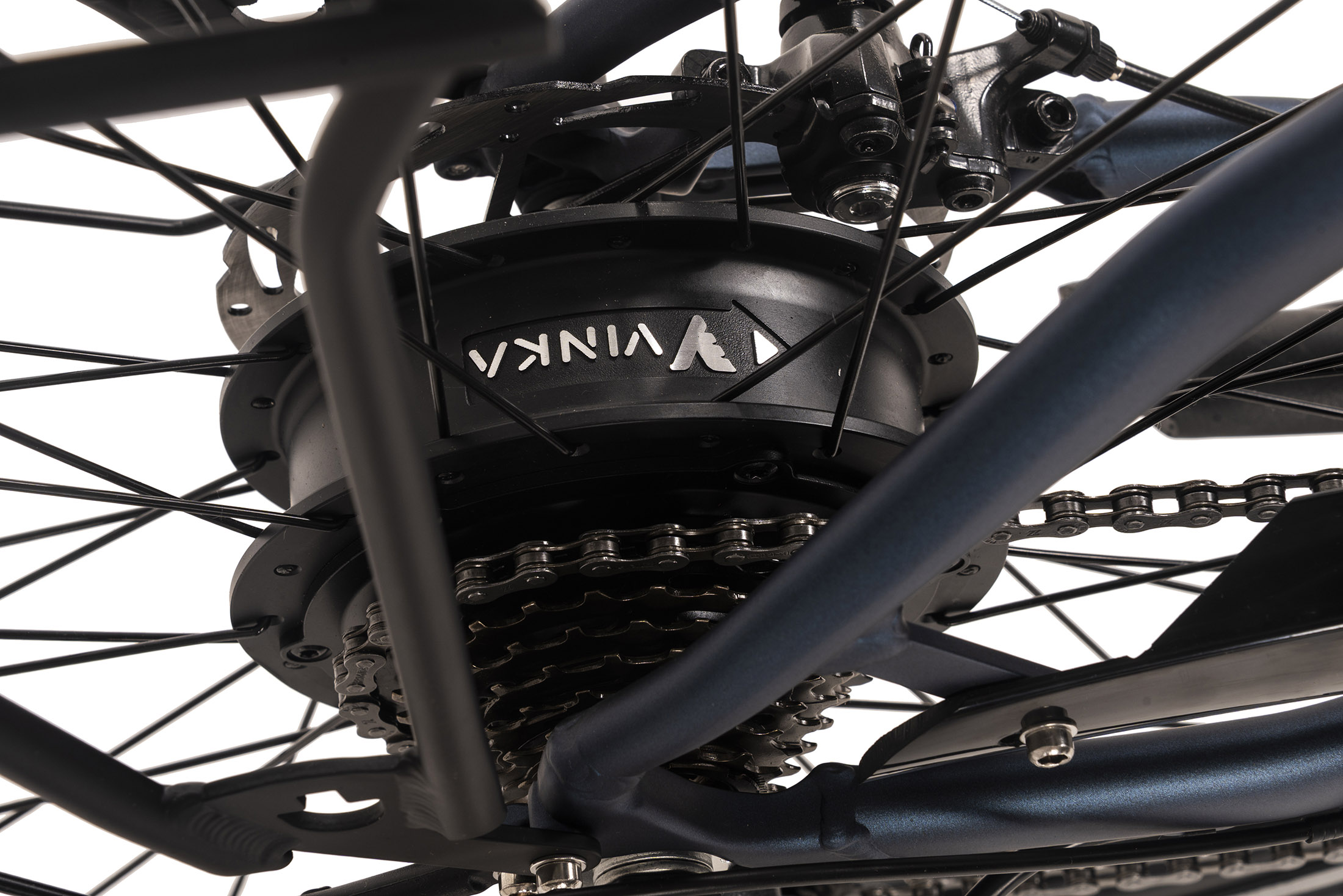 Nahaufnahme eines Fahrradrads mit dem Vinka-Logo auf dem schwarzen Motor. Kette, Zahnräder und Rahmenteile sind sichtbar.