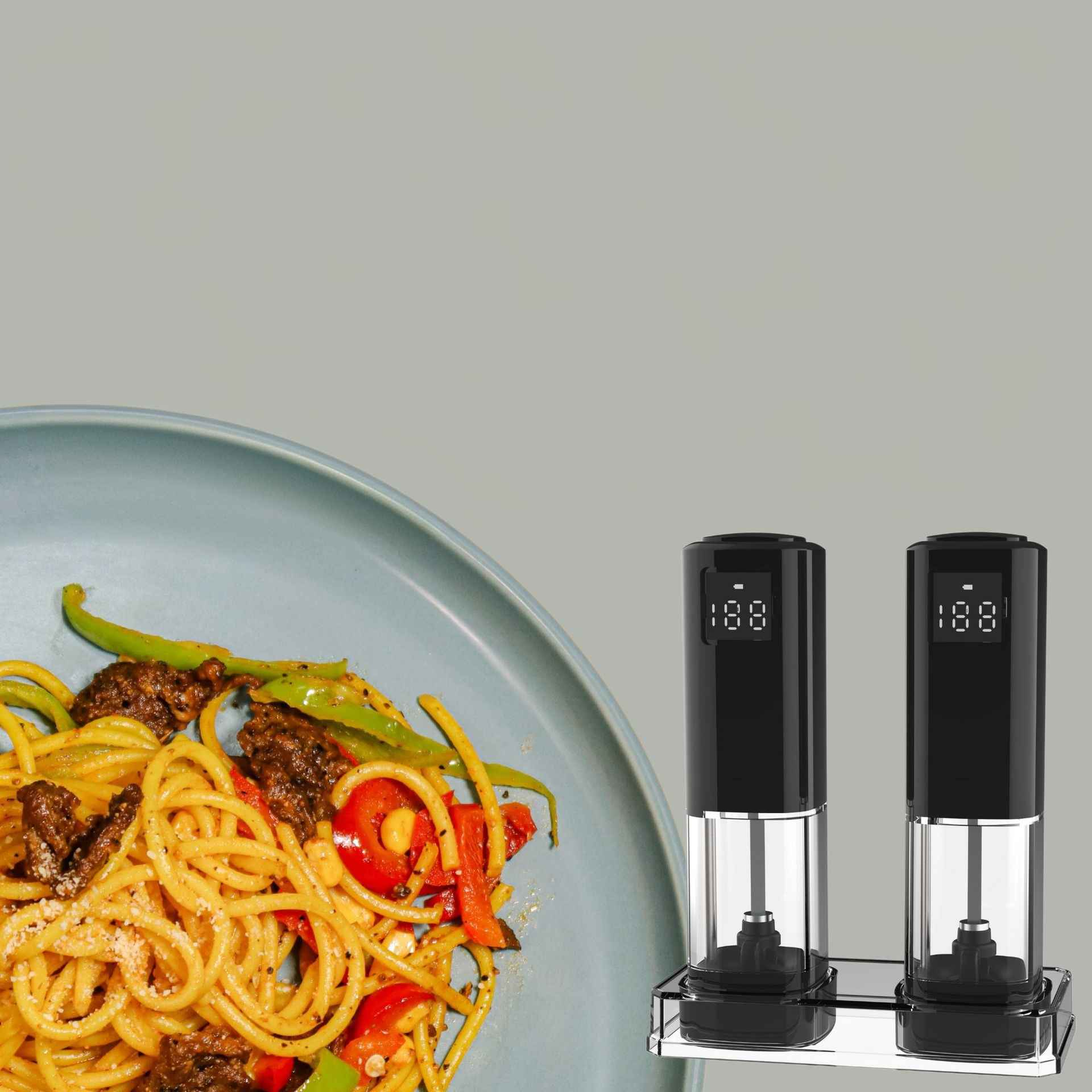 Spaghetti mit Gemüse auf einem Teller, Salz- und Pfeffermühlen im Hintergrund.