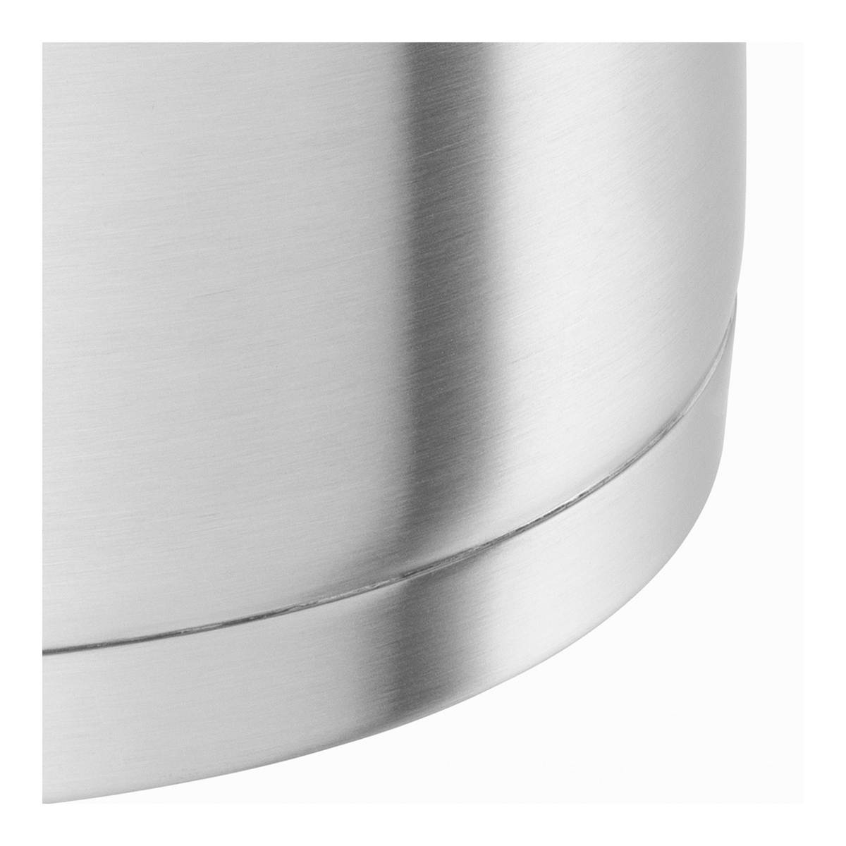 Zbliżenie błyszczącego, metalowego garnka. Powierzchnia odbija światło, a zakrzywiona krawędź jest widoczna na białym tle.