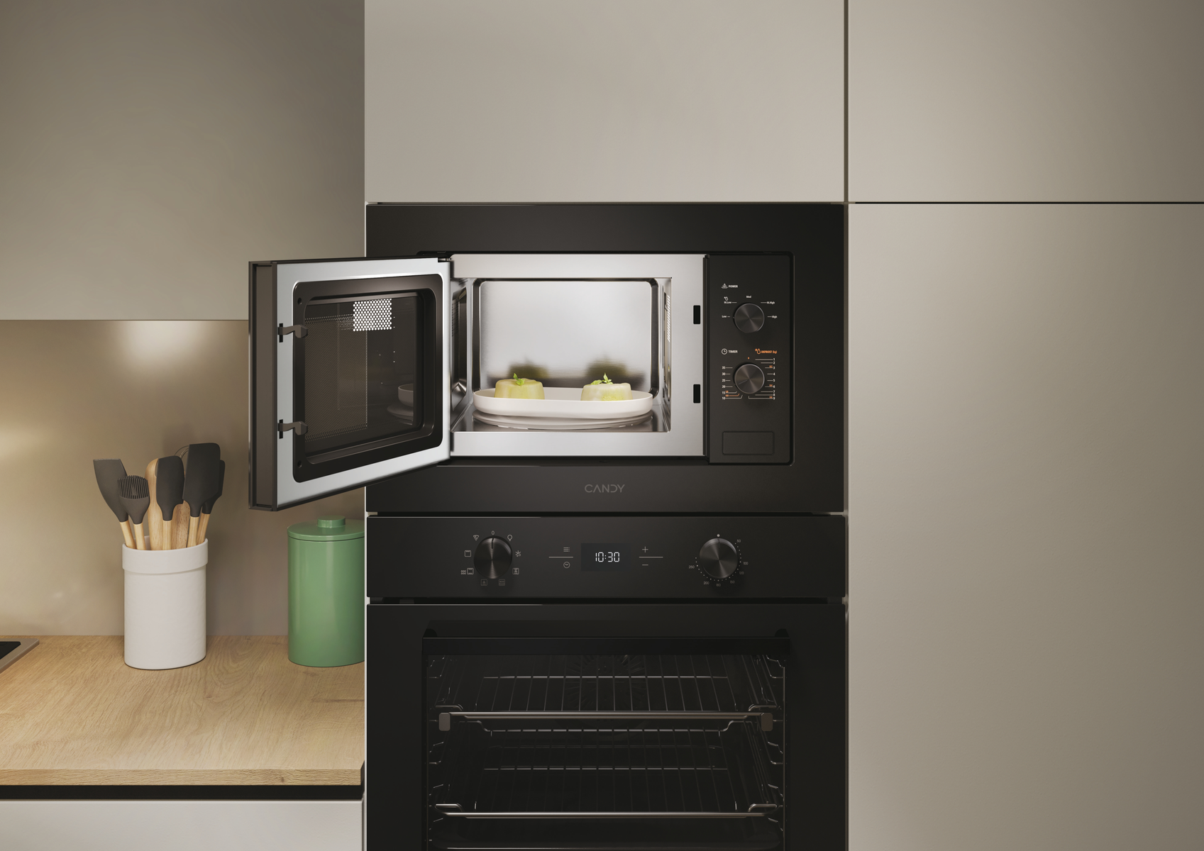 Un forno a microonde nero con la porta aperta, che mostra due dessert su un piatto bianco. Sotto c'è un forno nero.