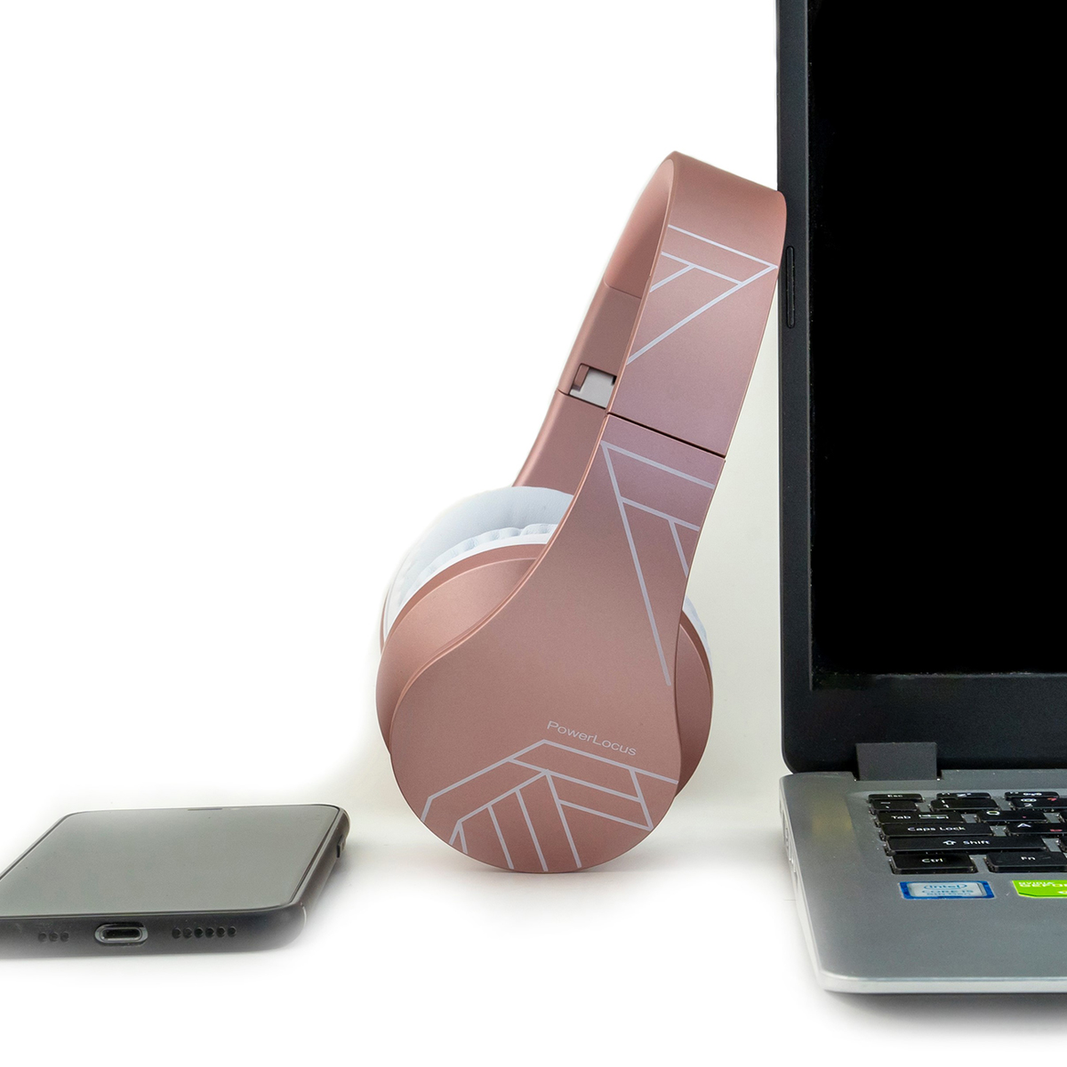 Cuffie color oro rosa, uno smartphone e un laptop su una superficie bianca. Le cuffie sono accanto al laptop.