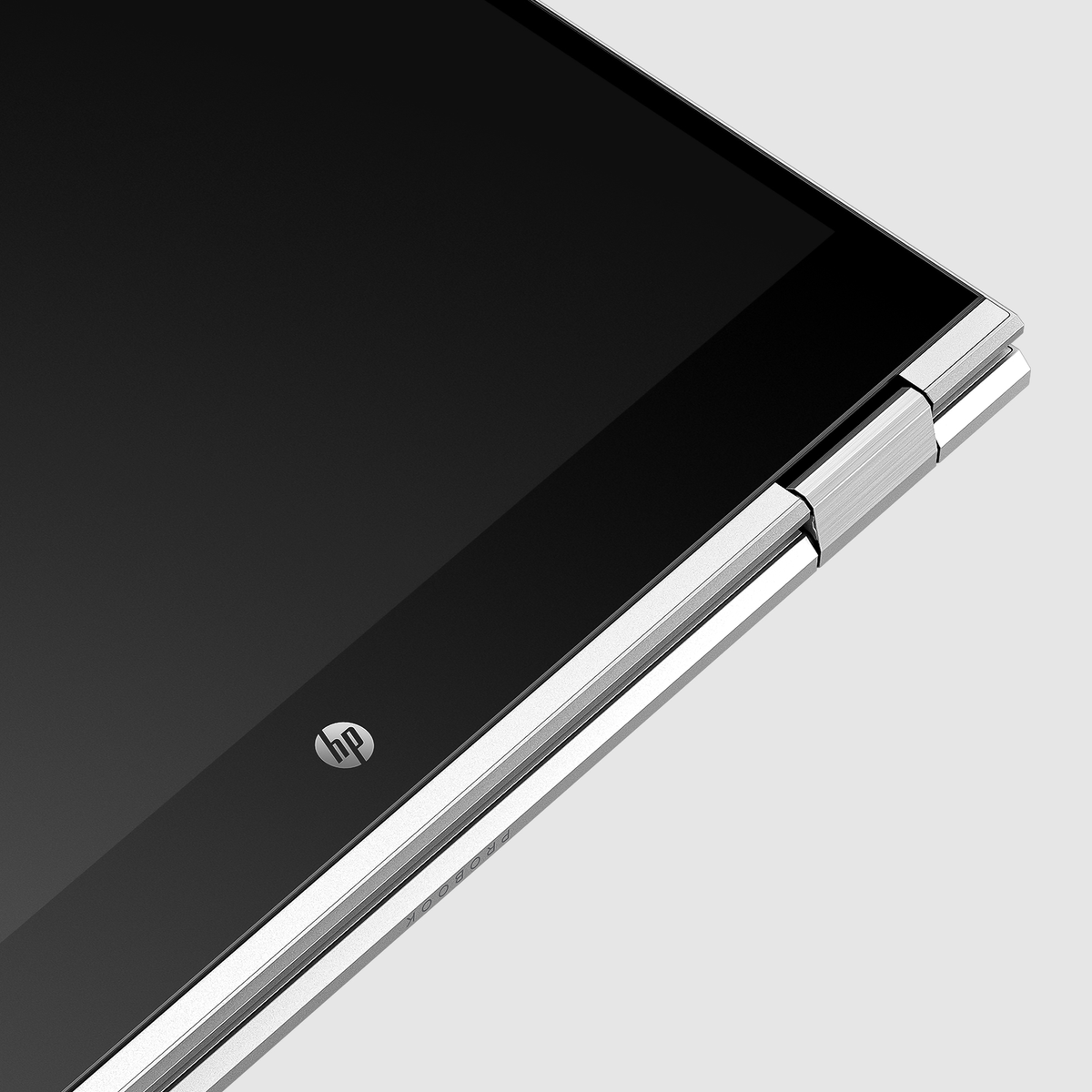 Zbliżenie laptopa HP ProBook. Ekran jest czarny, a ramka srebrna. Widoczne logo HP. Tło jest jasnoszare.