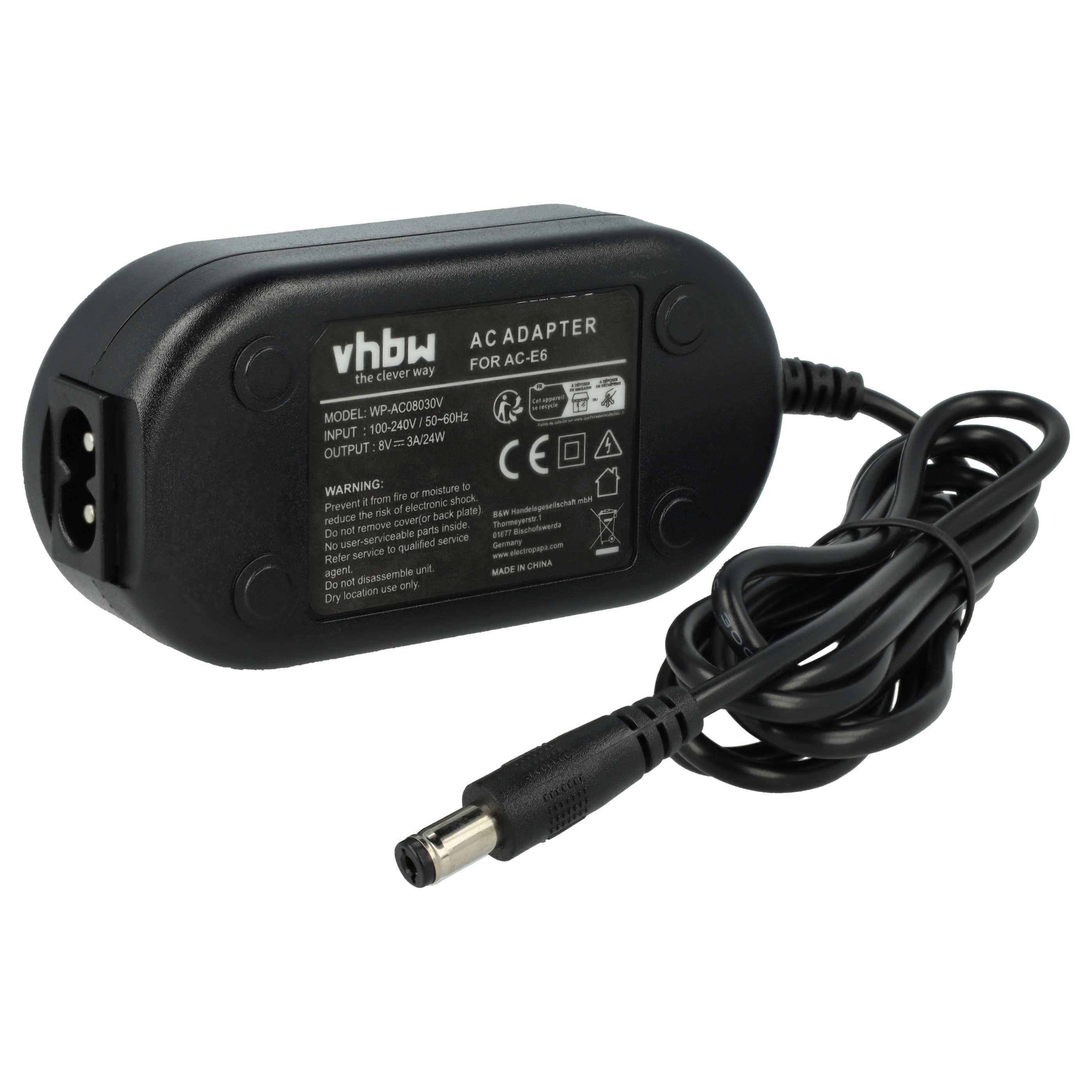 Schwarzes Netzteil für eine Kamera mit Netzkabel. Der Adapter hat Etiketten und einen Netzstecker.