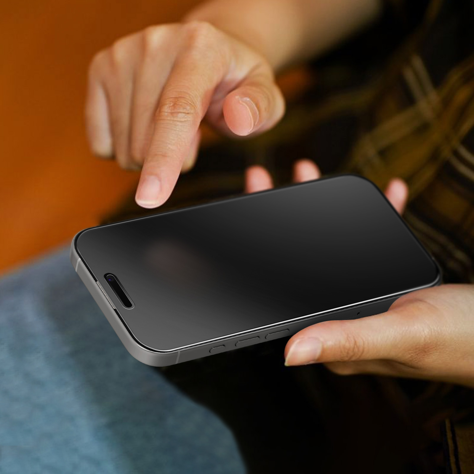Le mani di una persona che tiene uno smartphone nero, con un dito che tocca lo schermo. Lo sfondo è sfocato.