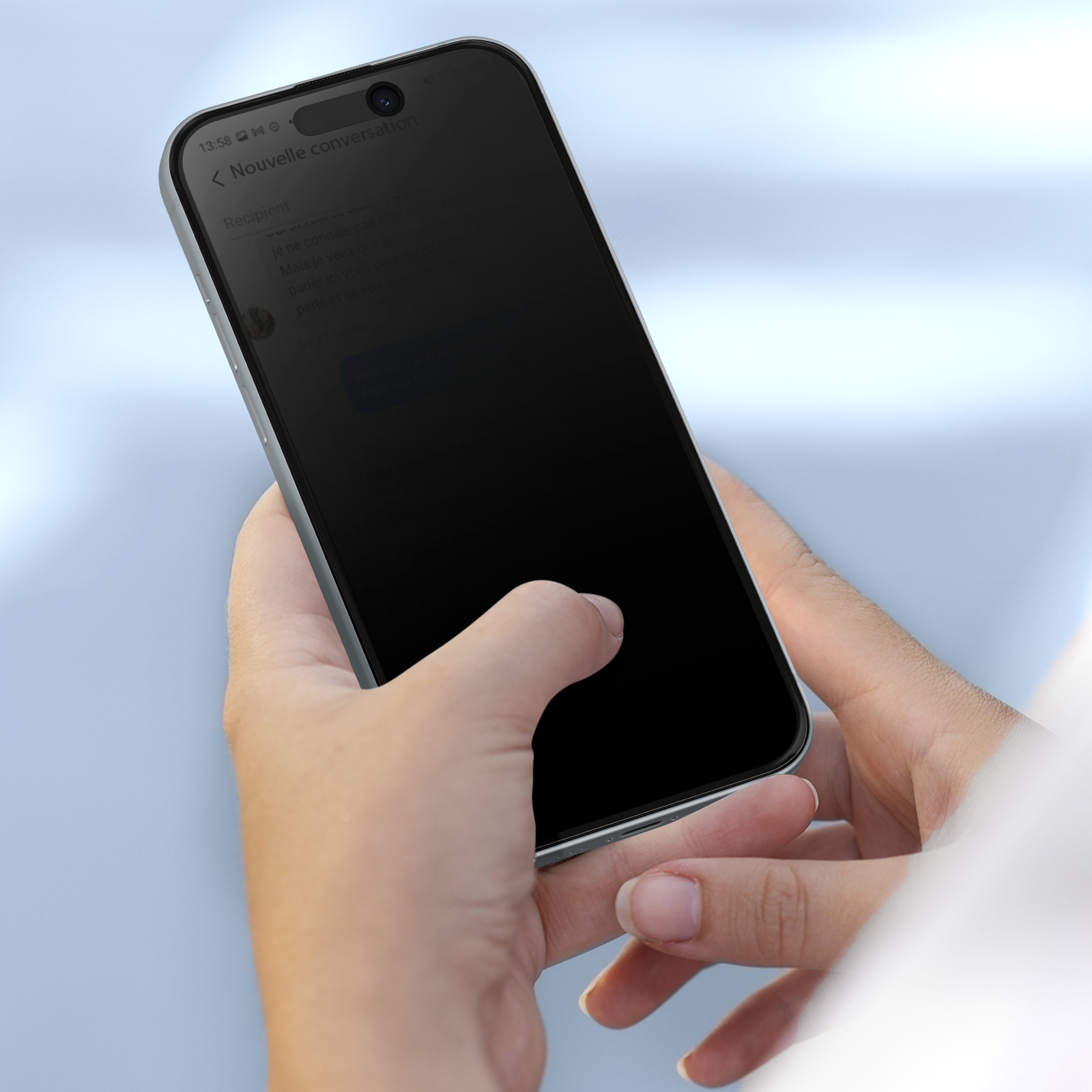 Una persona tiene in mano un telefono con schermo nero. Il telefono è argento, lo sfondo è blu sfocato.