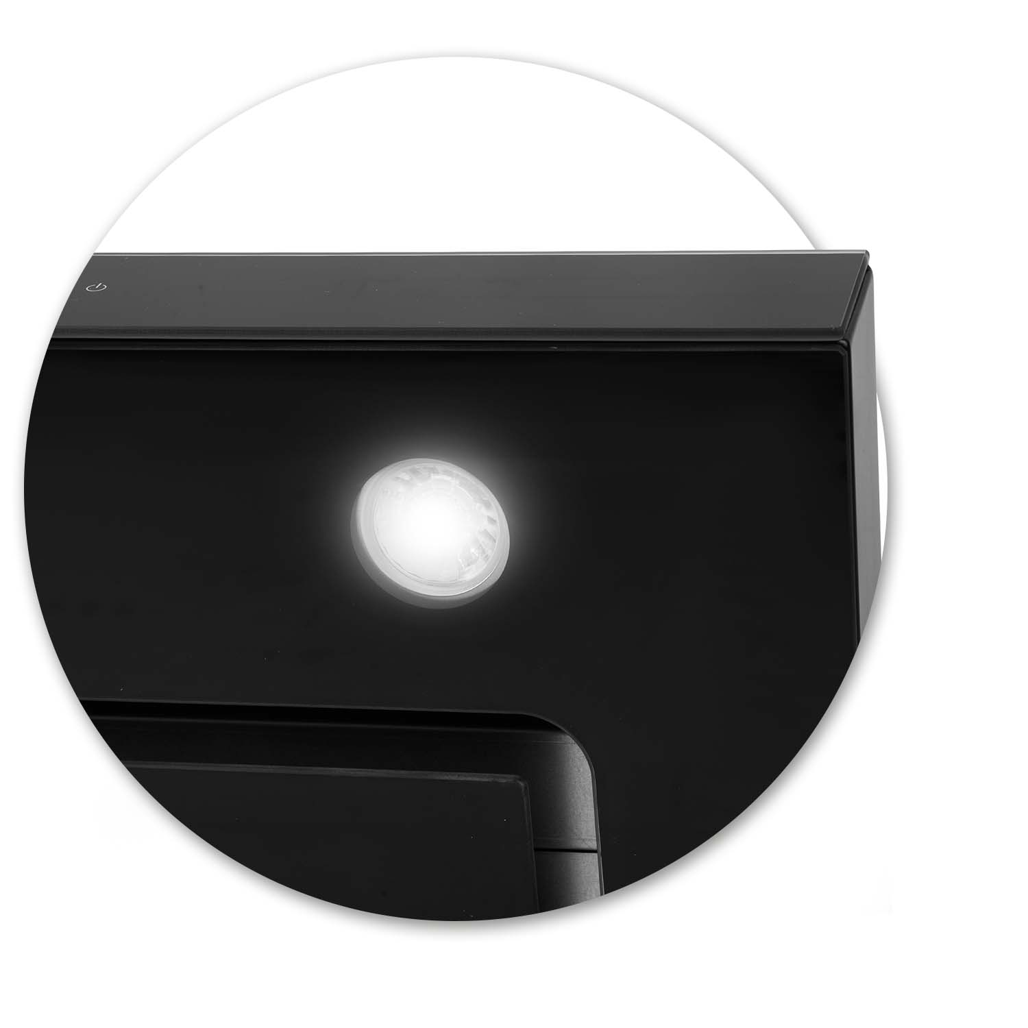 Zbliżenie czarnego urządzenia z jasnym, okrągłym światłem. Światło jest wyśrodkowane. Po lewej stronie u góry widoczny jest symbol zasilania.