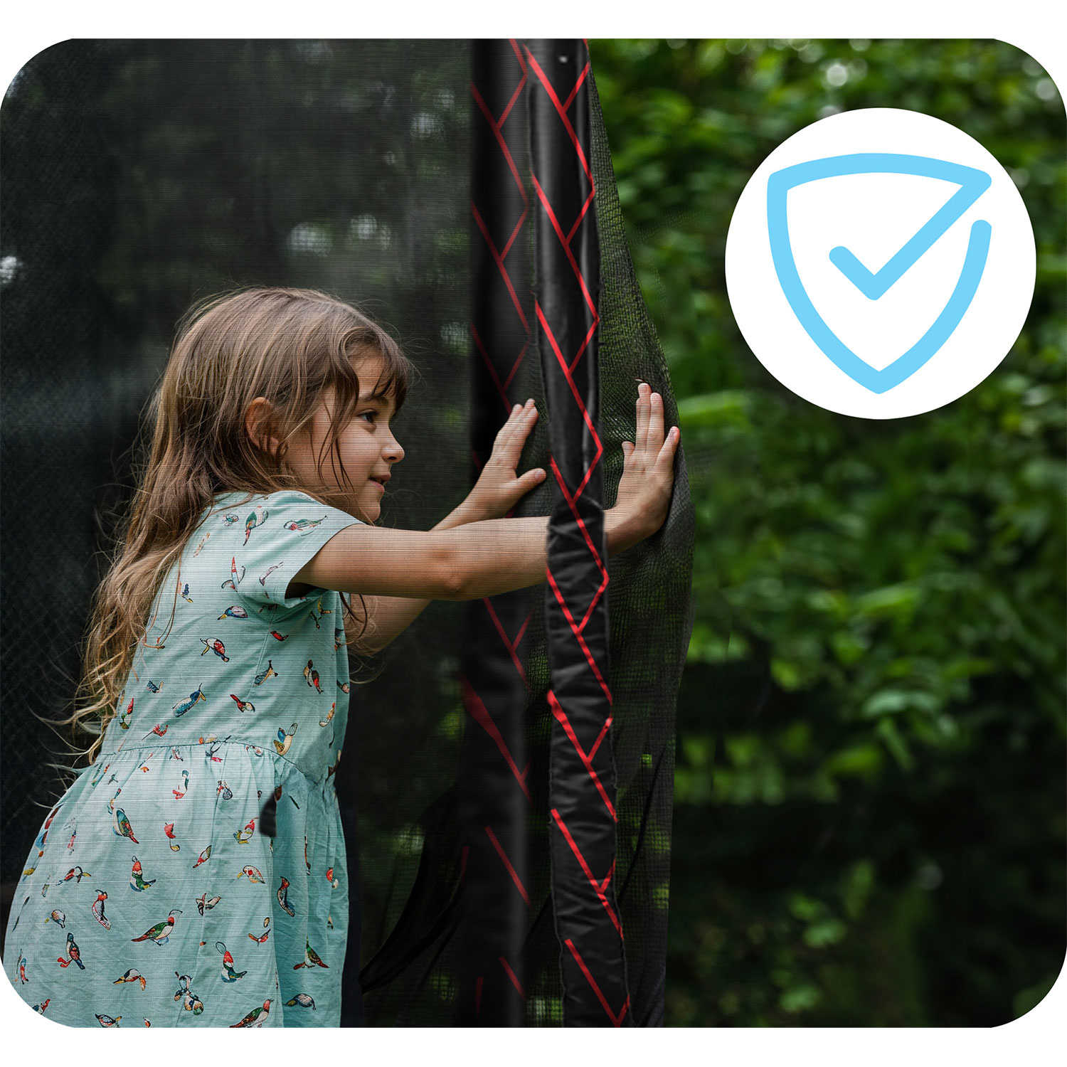 Dziewczyna w sukience z nadrukiem ptaków dotyka siatki trampoliny. Ikona bezpieczeństwa w tle, z zielonymi liśćmi.