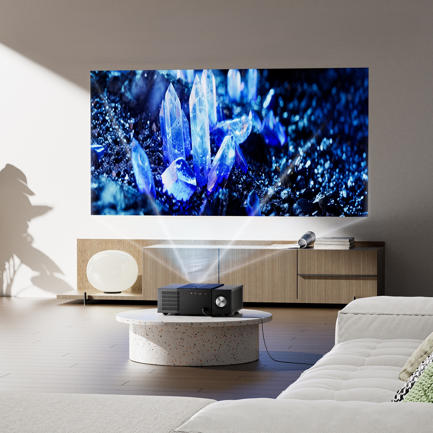 Une configuration de cinéma maison présente un projecteur affichant une image de cristal bleu. Un projecteur noir est posé sur une table ronde. Un canapé blanc est devant.