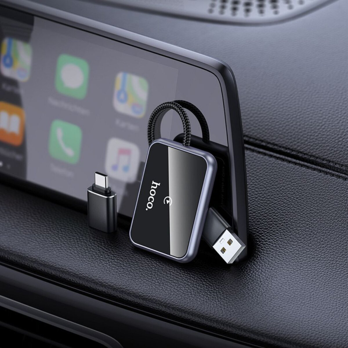Un teléfono que muestra aplicaciones está montado en el tablero de un automóvil. Un adaptador Hoco negro y un cable USB están conectados al teléfono.