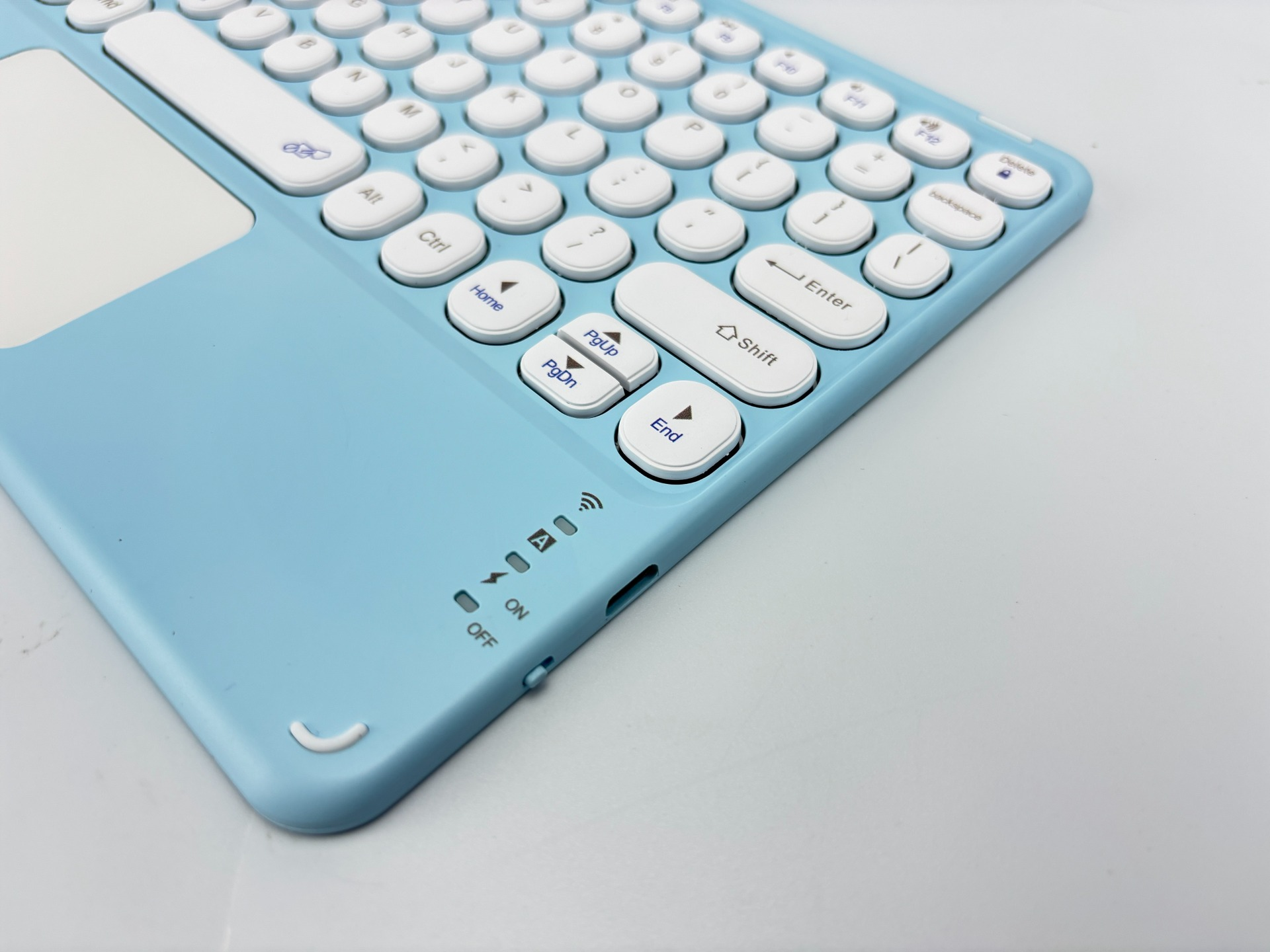 Eine hellblaue kabellose Tastatur mit weißen Tasten und einem Touchpad. Die Tasten sind mit Buchstaben und Symbolen beschriftet.