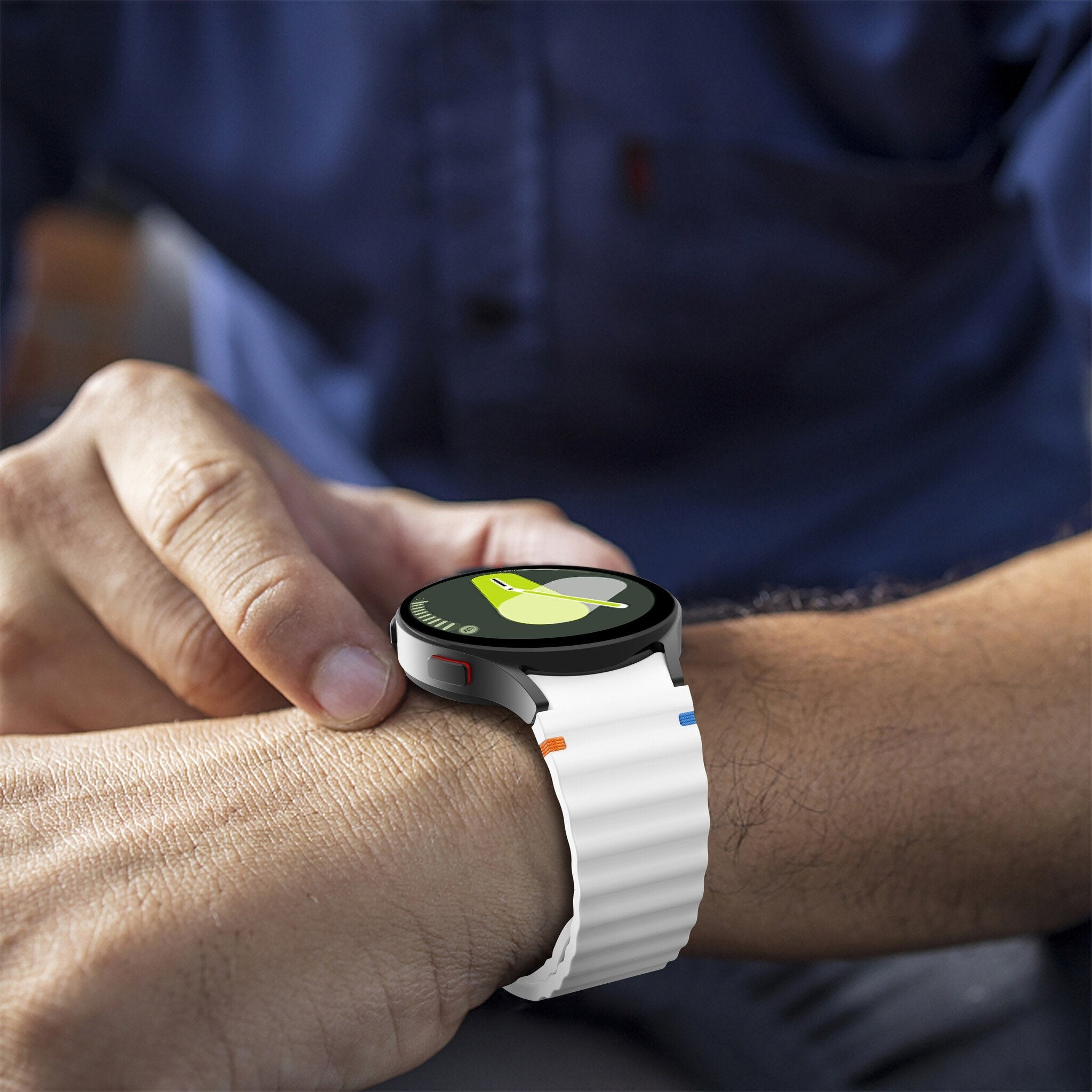 Eine Person trägt eine Smartwatch mit weißem Armband. Die Uhr zeigt eine grün-gelbe Grafik. Der Arm der Person ist sichtbar.