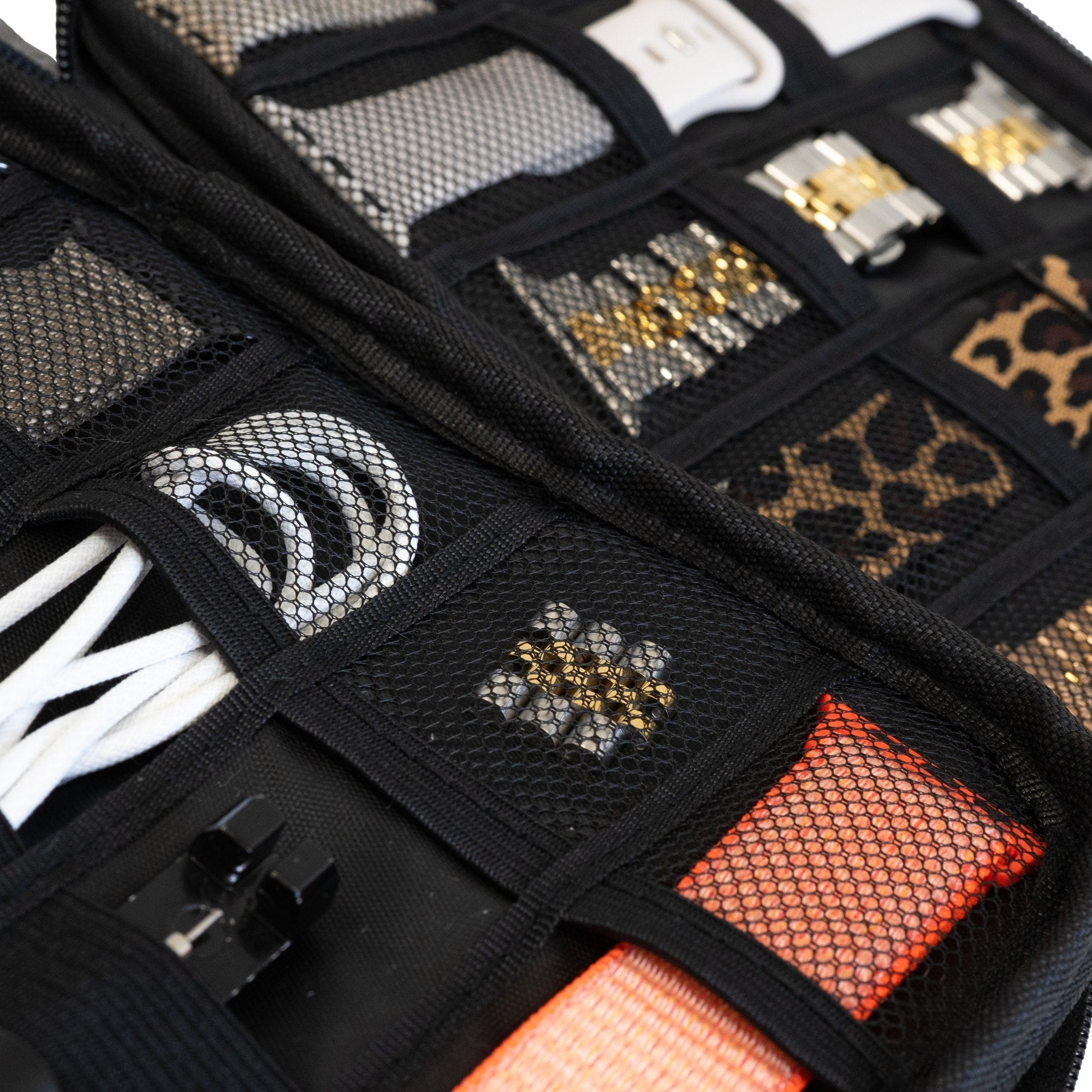 Schwarzer Organizer mit Fächern für Armbänder, Kabel und kleine Gegenstände. Einige Fächer sind aus Netzstoff.