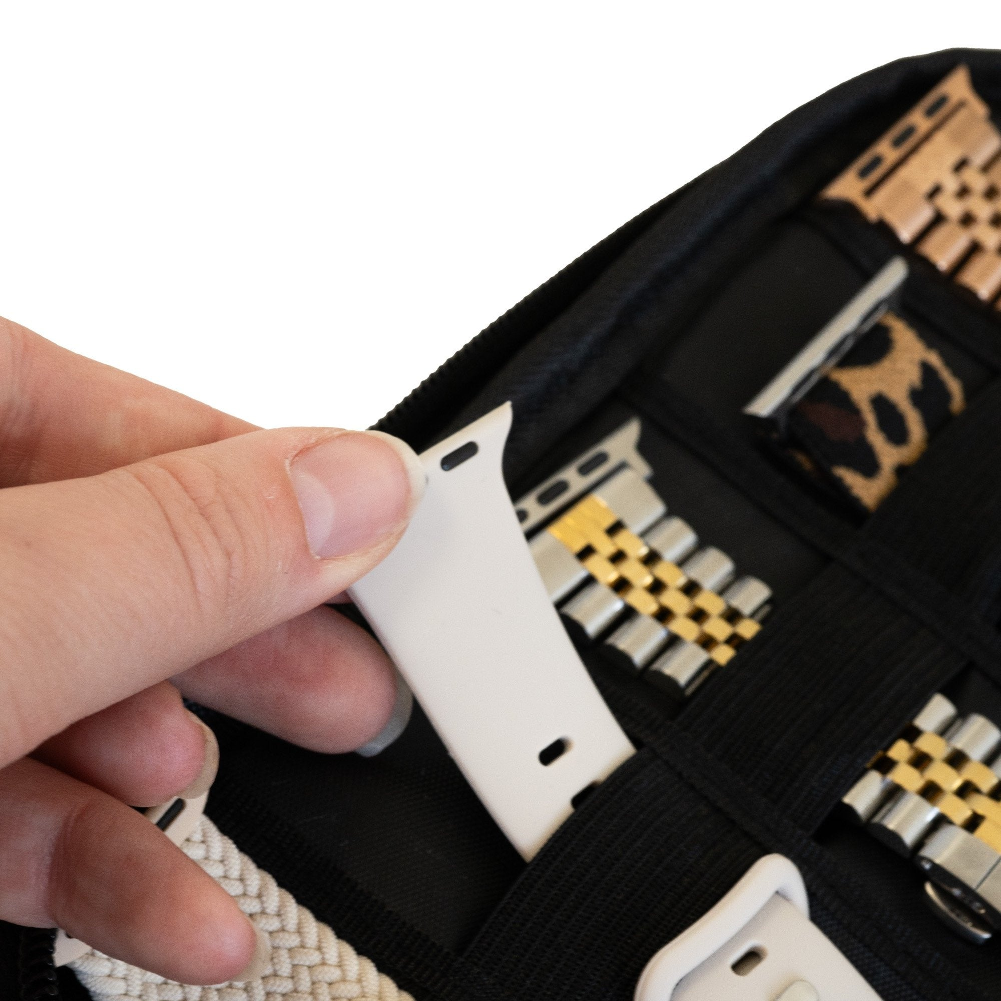 Eine Hand hält ein weißes Uhrenarmband neben Uhrenarmbändern verschiedener Designs in einem schwarzen Organizer.