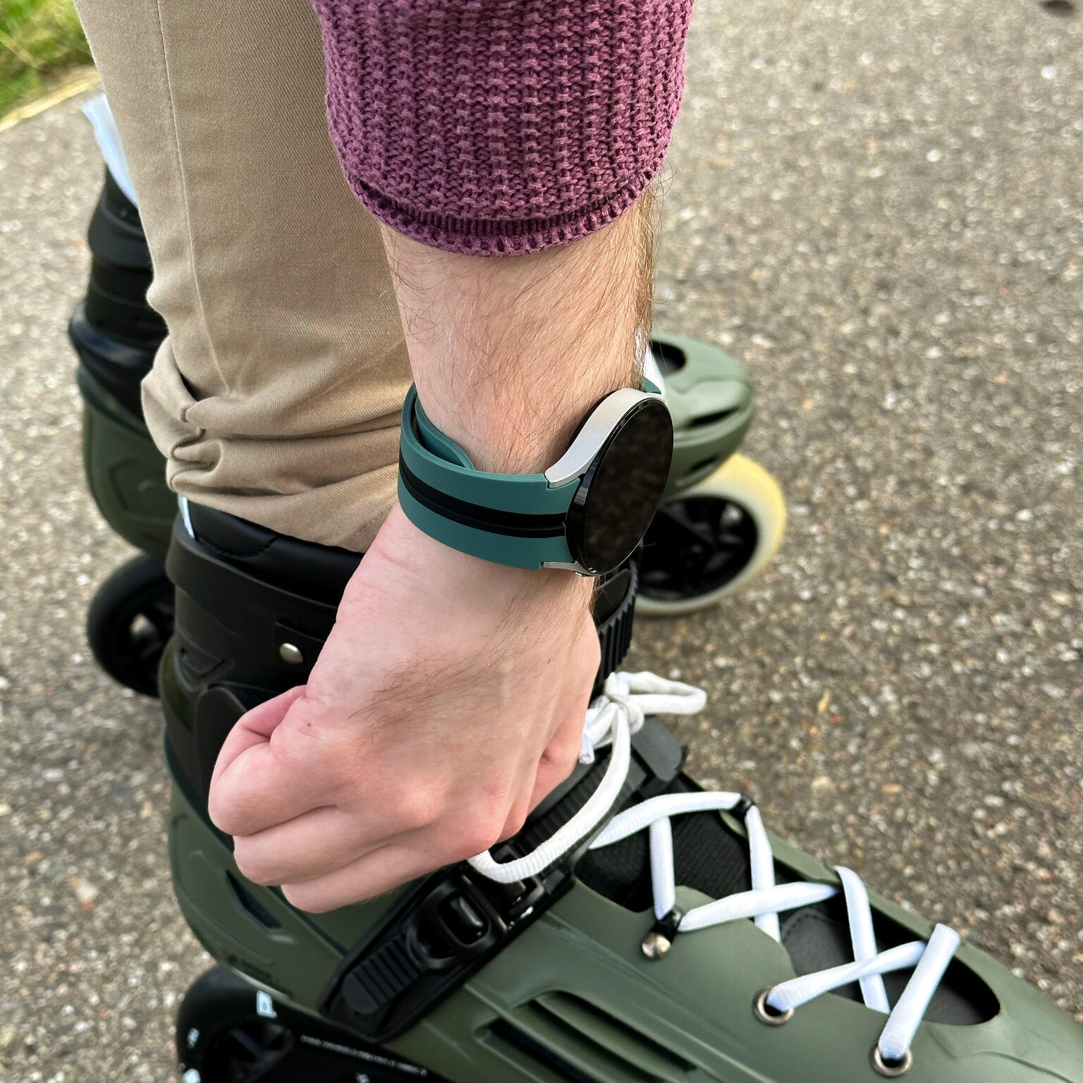 Person trägt Rollschuhe und eine Smartwatch. Die Rollschuhe sind grün, die Uhr hat ein grünes Armband. Die Person trägt einen lila Pullover.