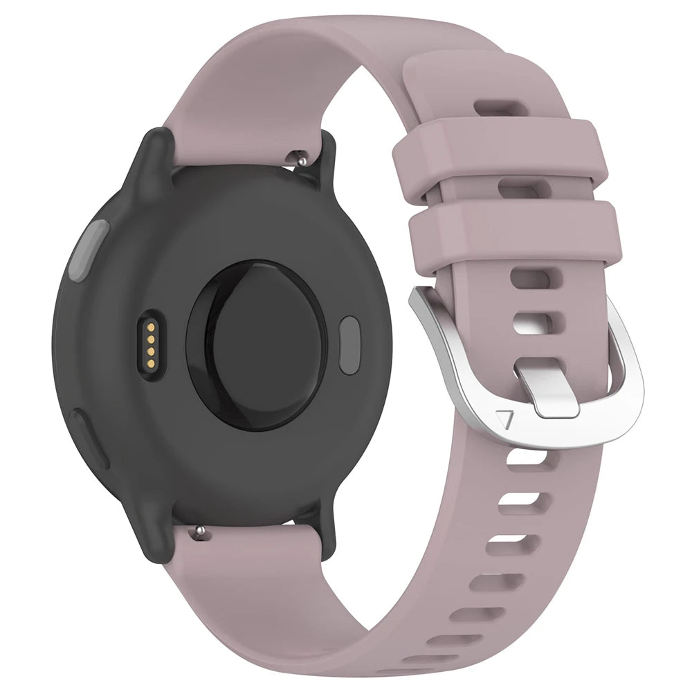 Eine Smartwatch mit schwarzem Gehäuse und helllila Armband, silberne Schnalle. Die Rückseite hat Sensoren und einen Ladeanschluss.