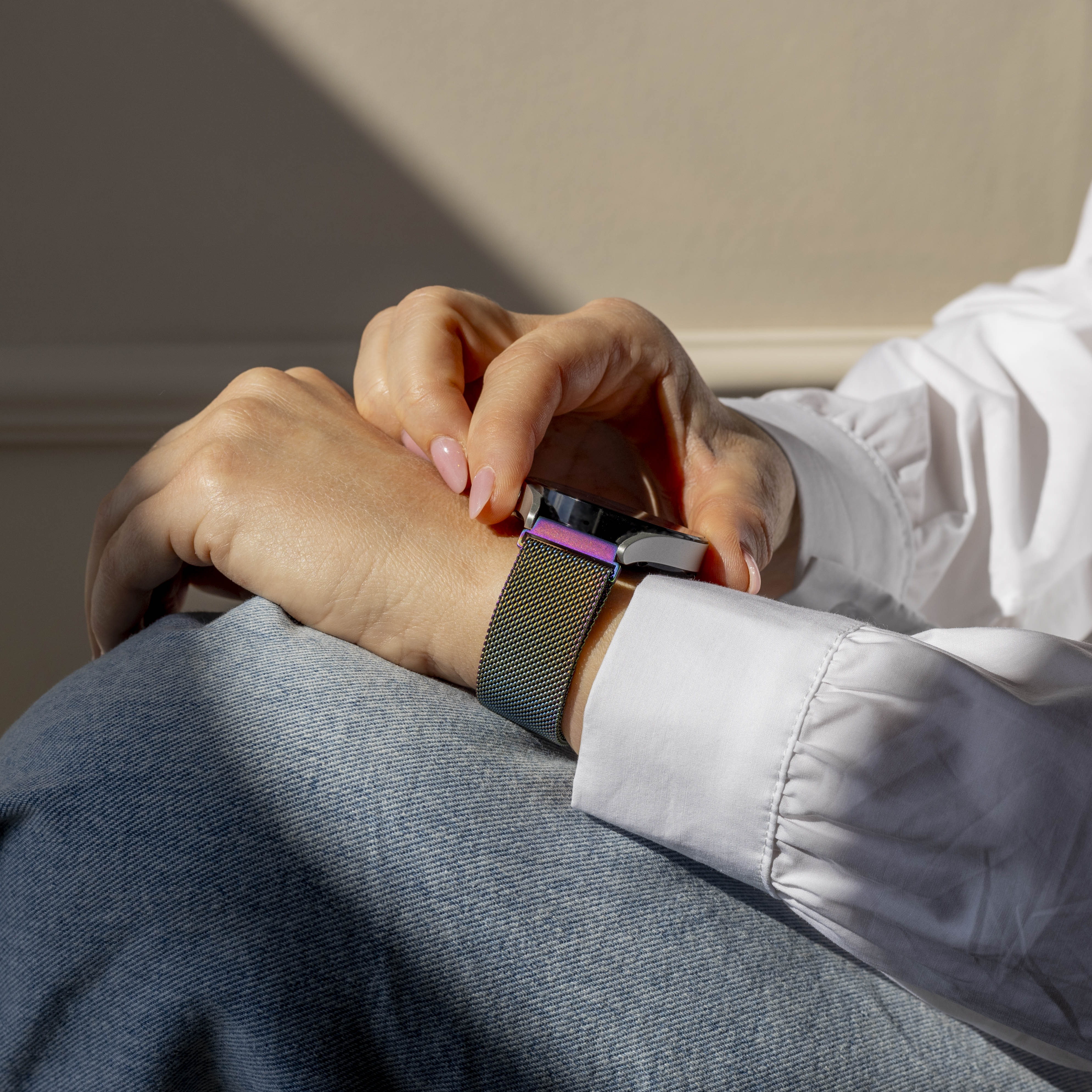 Eine Person, die eine Smartwatch mit einem bunten Armband trägt. Die Person trägt ein weißes Hemd und Jeans.