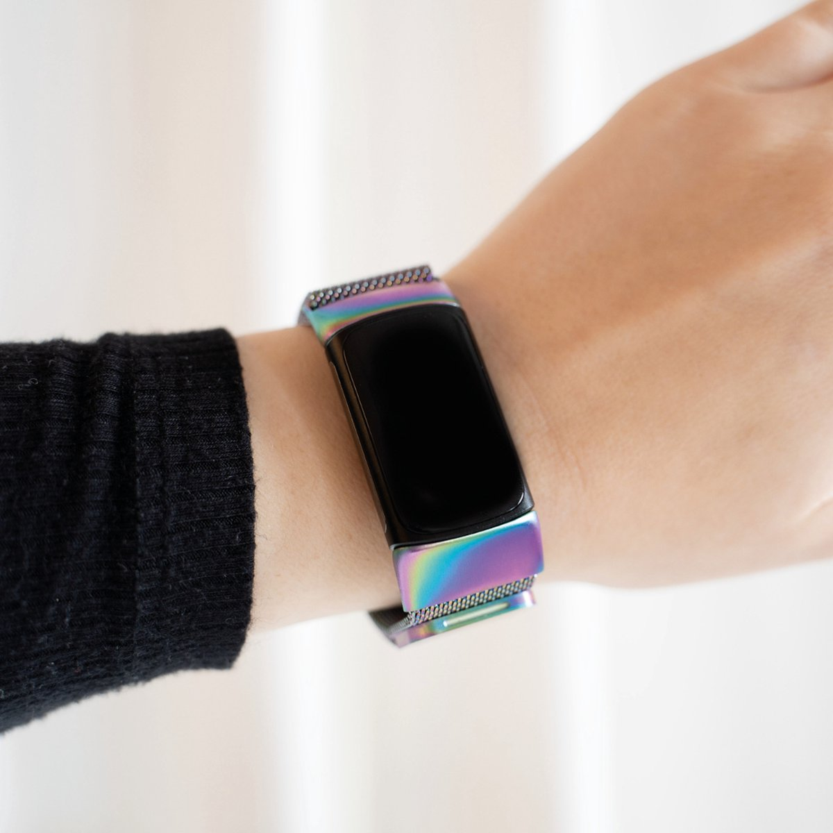Ein Handgelenk mit einer Smartwatch. Das Armband hat ein regenbogenfarbenes Metallic-Finish. Der Bildschirm ist schwarz.
