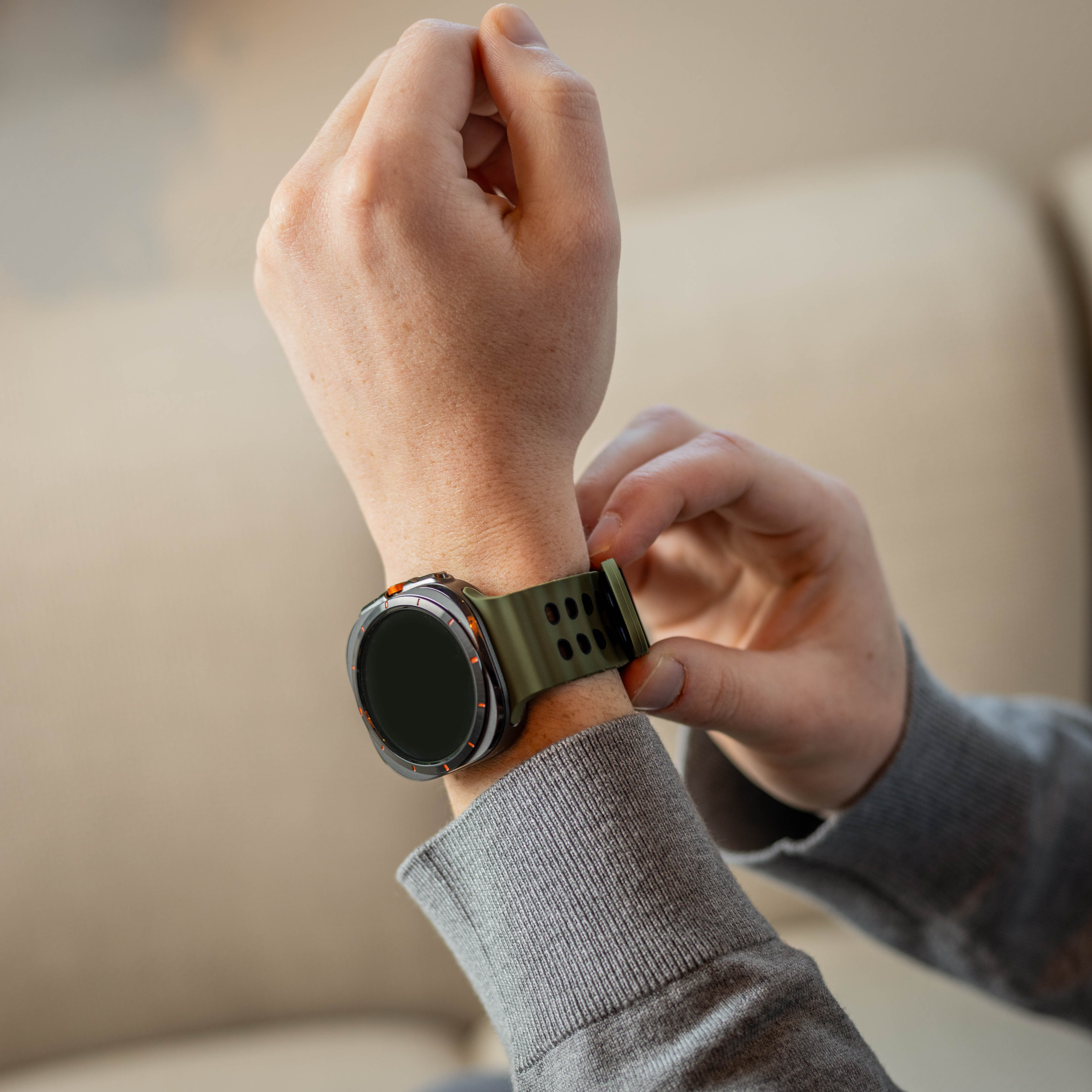 Eine Person justiert eine Smartwatch an ihrem Handgelenk. Die Uhr hat ein grünes Armband und einen schwarzen Bildschirm.