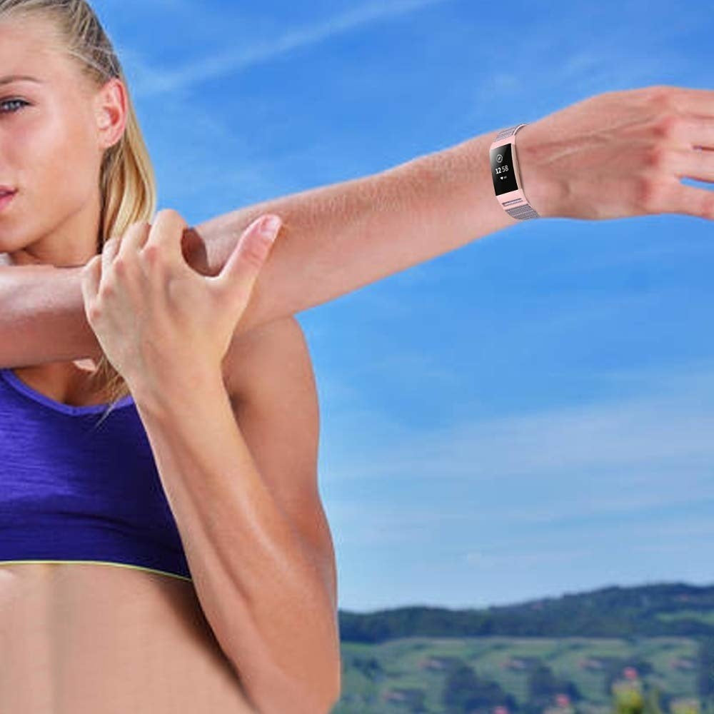 Frau dehnt sich, trägt einen lila Sport-BH, eine Smartwatch, vor blauem Himmel.