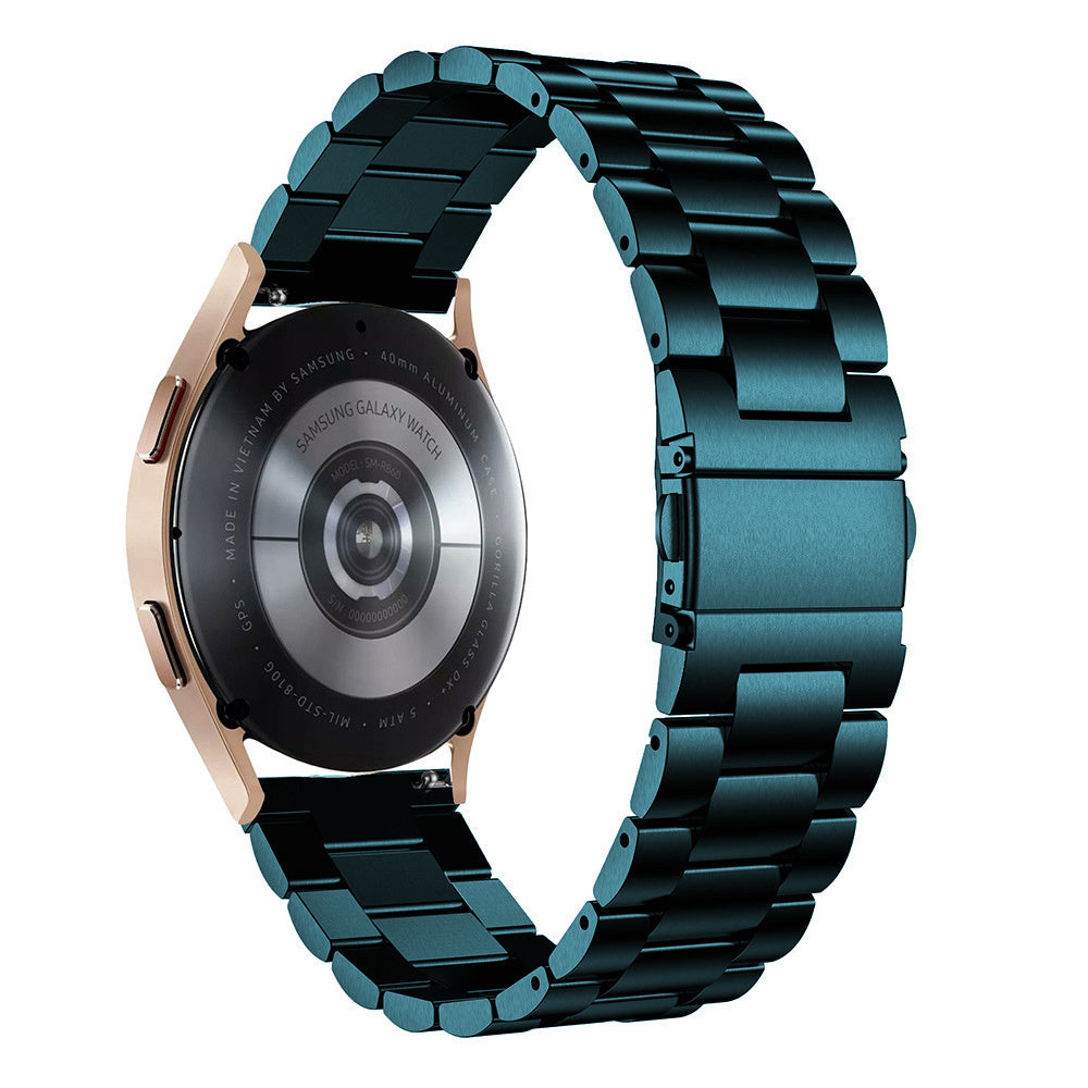 Ein tealfarbenes Metallarmband ist um eine roségoldene Uhr gewickelt. Die Rückseite der Uhr ist sichtbar und zeigt Details und Text.